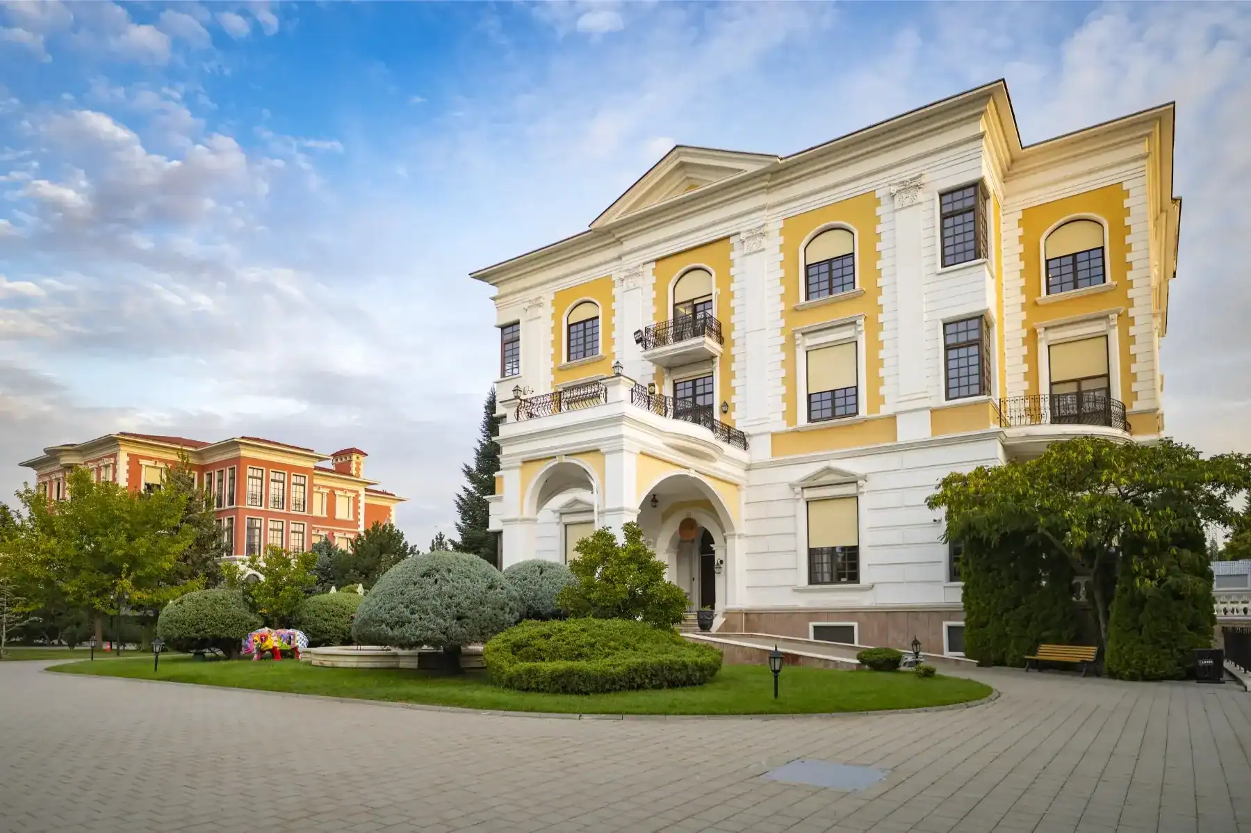 Elegant historic school building with yellow and white facade in a lush green setting.