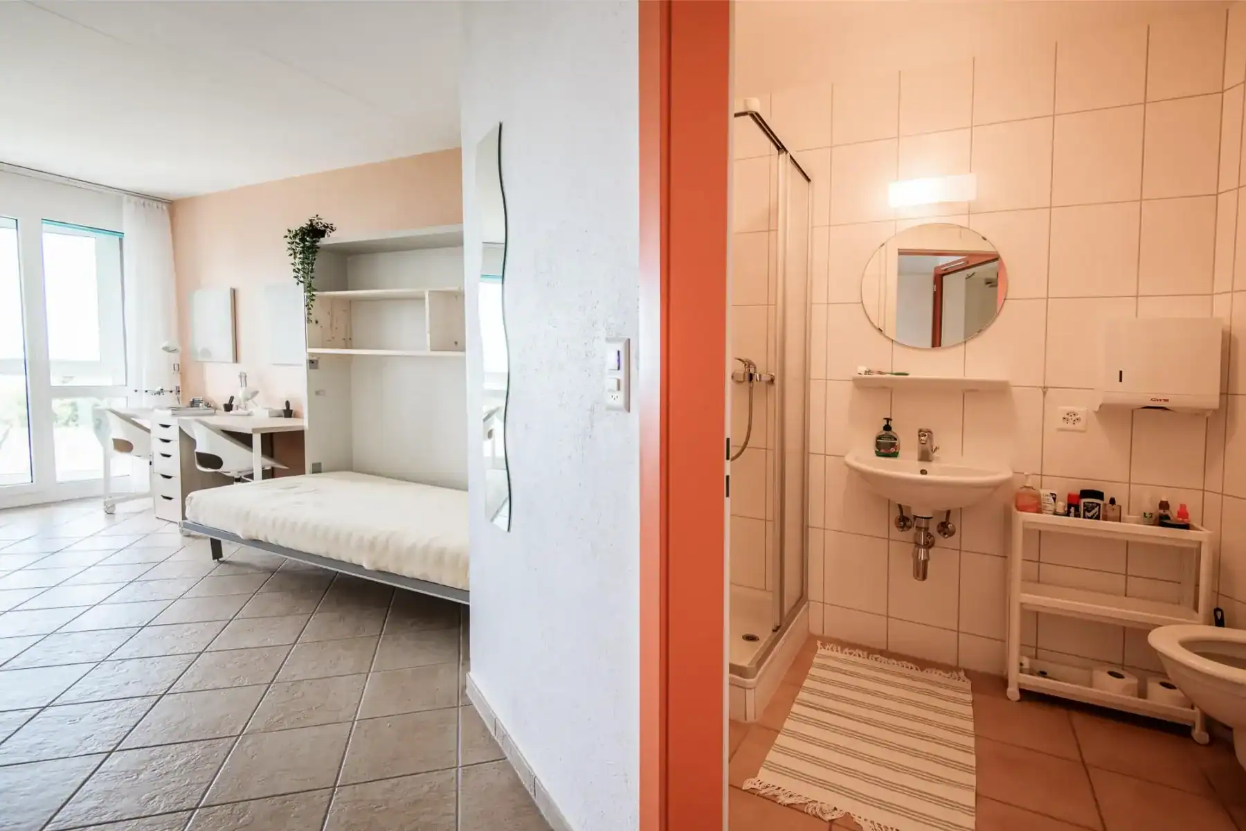 Comfortable dorm room with study area and natural light, adjacent to a clean, well-equipped bathroom.