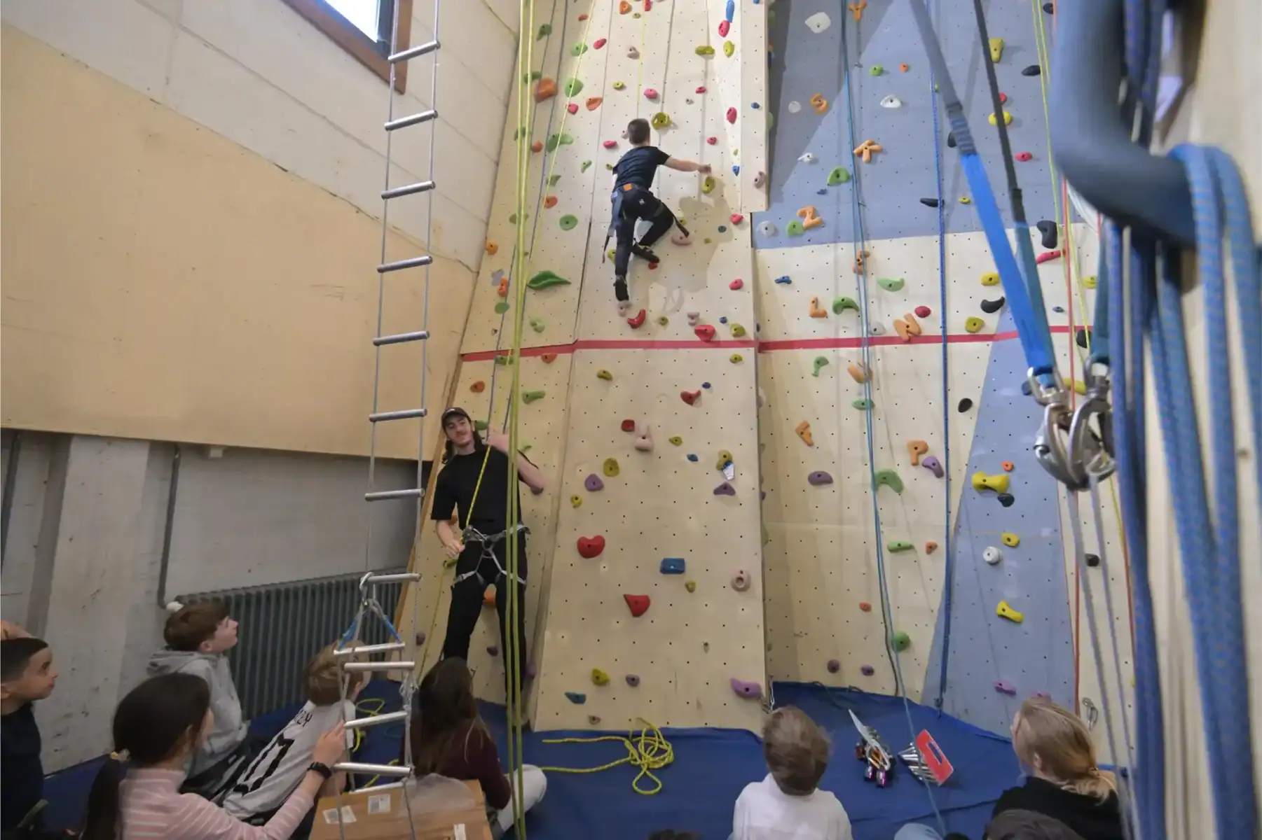 Indoor rock climbing wall with children and instructor at International School of Brussels.