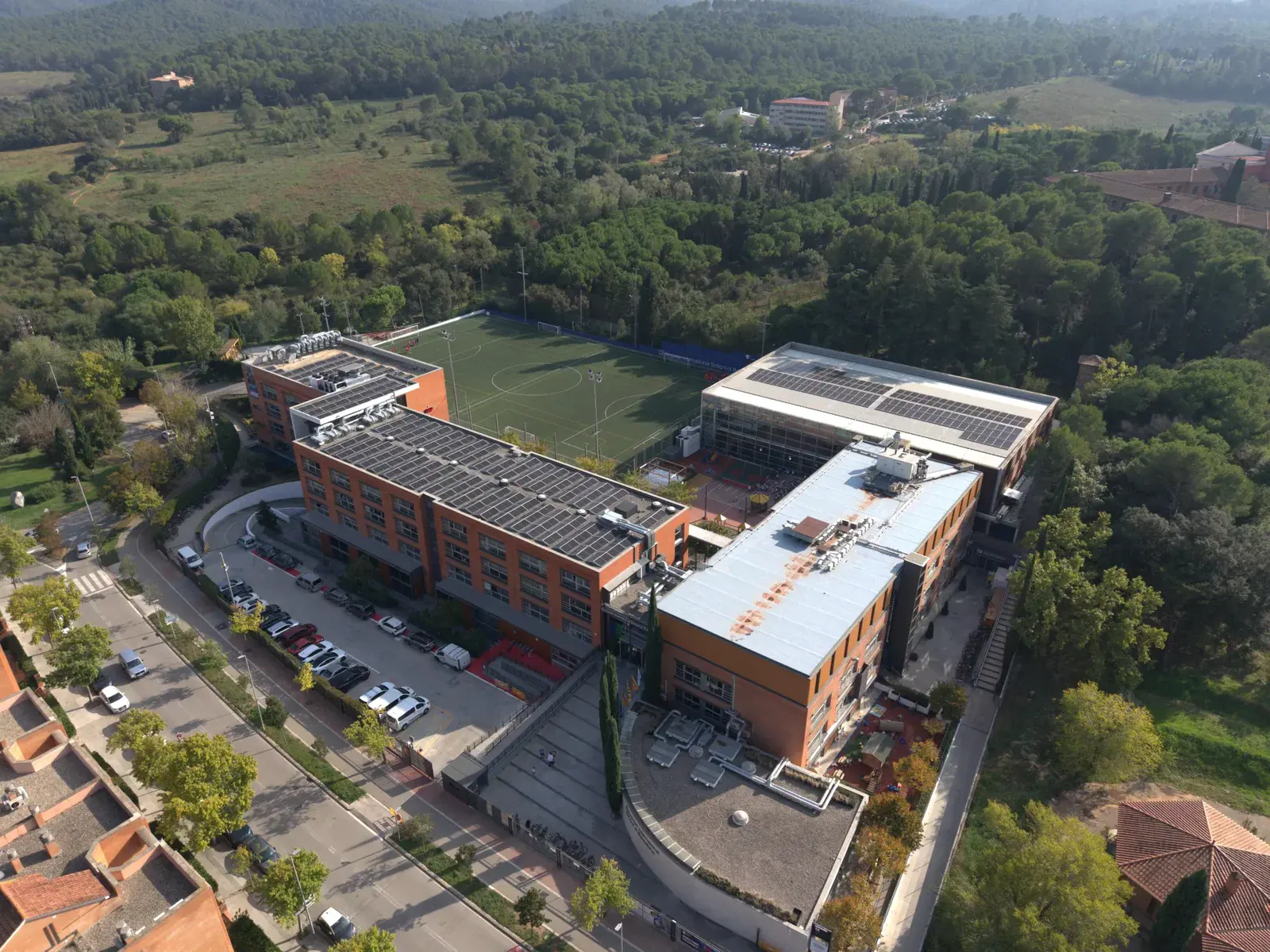 European International School of Barcelona campus aerial view with football field and buildings.