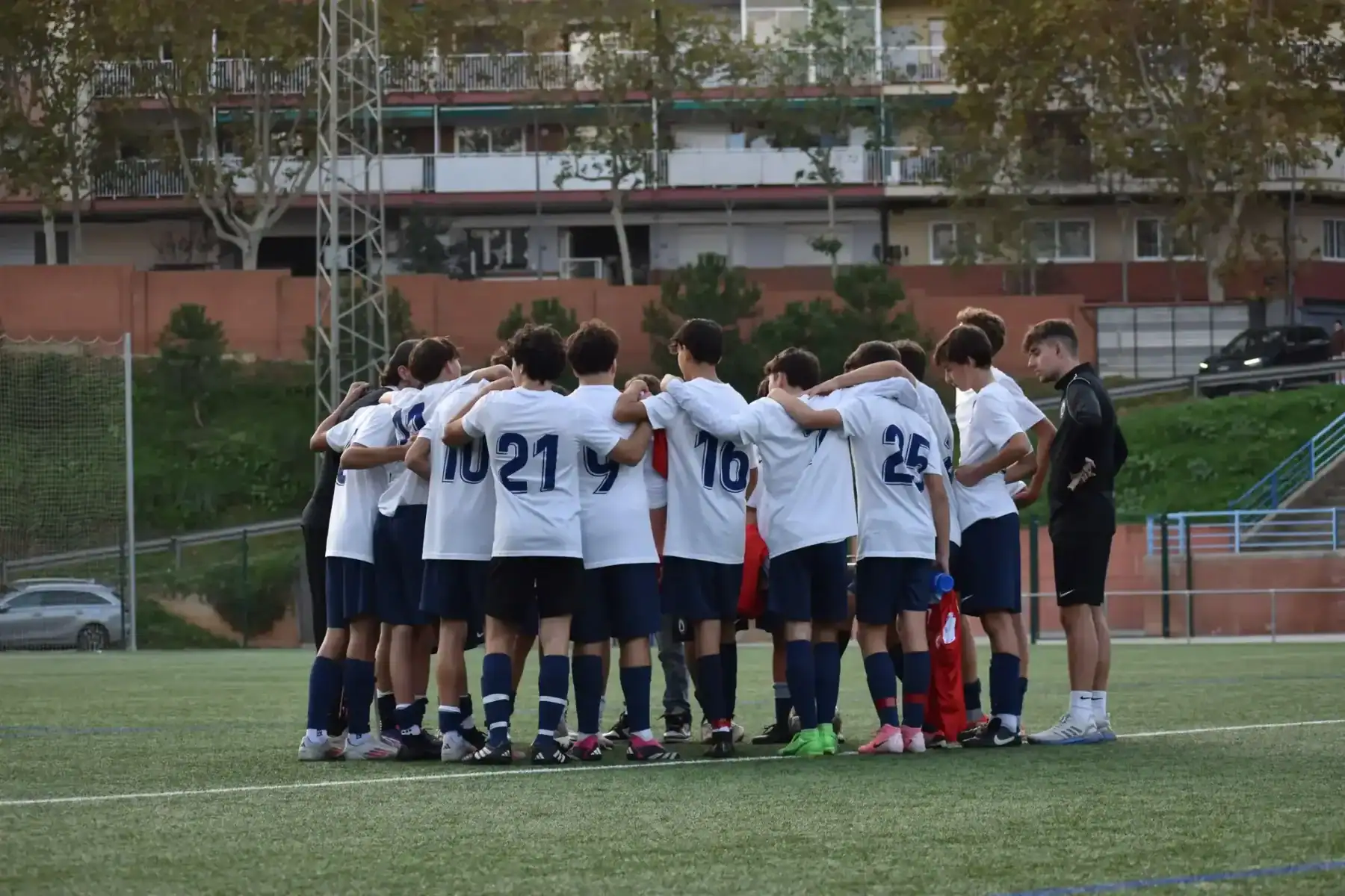 Youth soccer team huddling before match at American School of Barcelona.