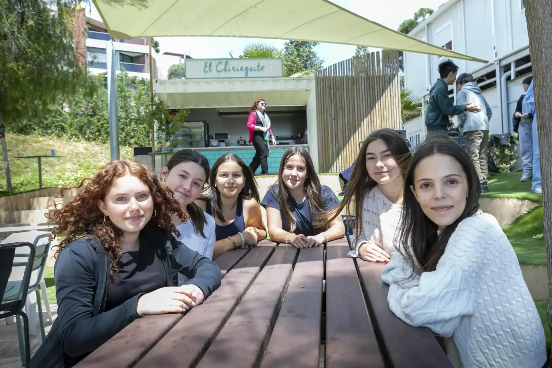American School of Barcelona students studying outdoors in a sunny campus setting.