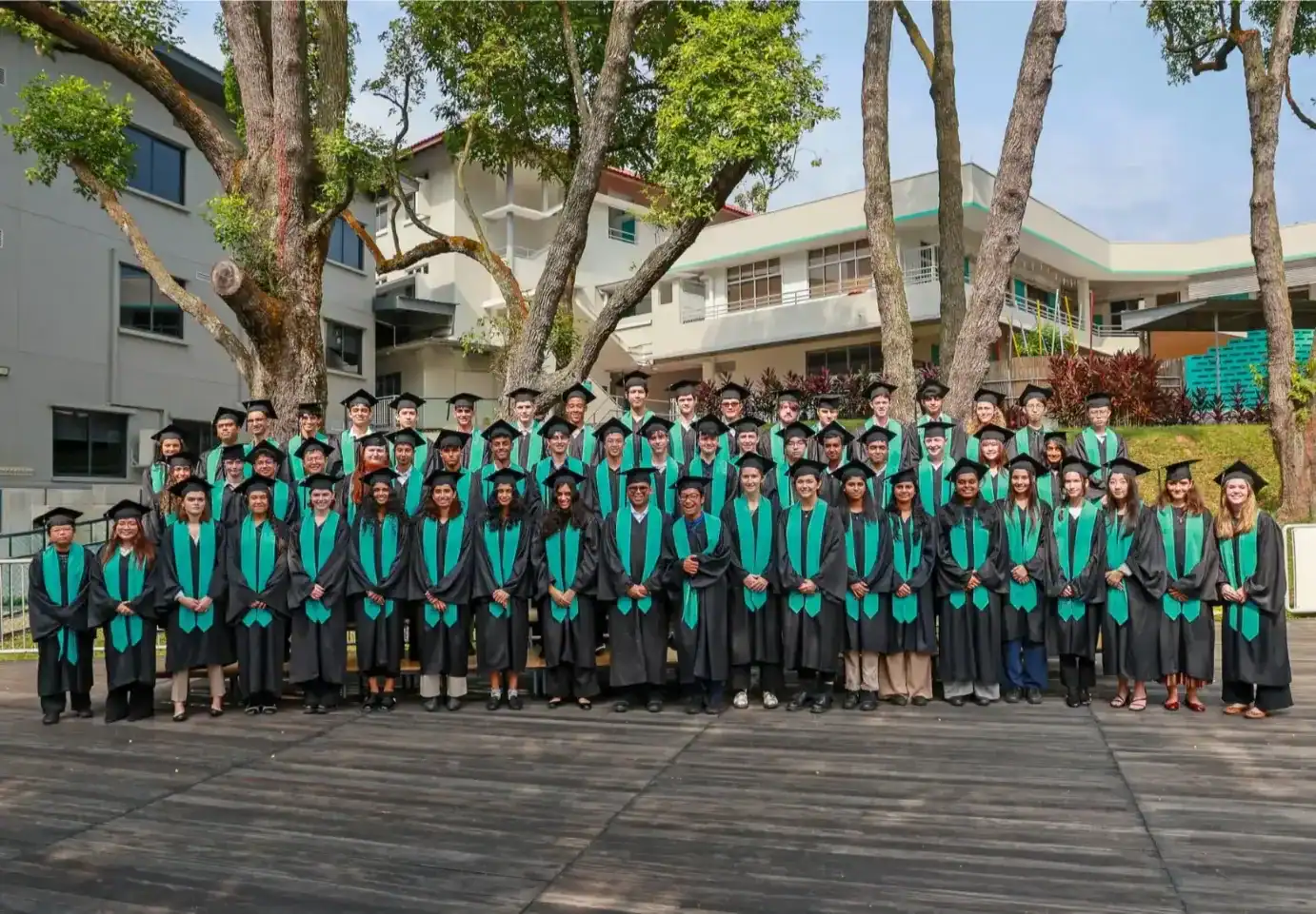 Group of graduates in caps and gowns outdoors at Dover Court International School.