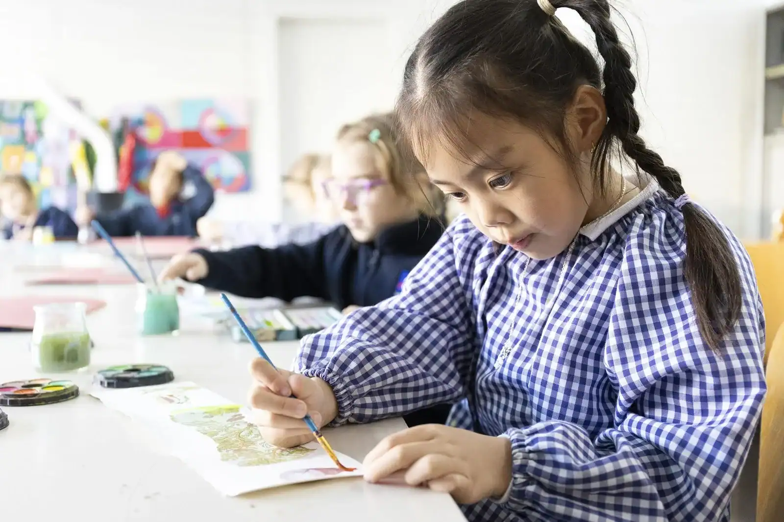 Young students painting at a classroom table, focusing on art project.