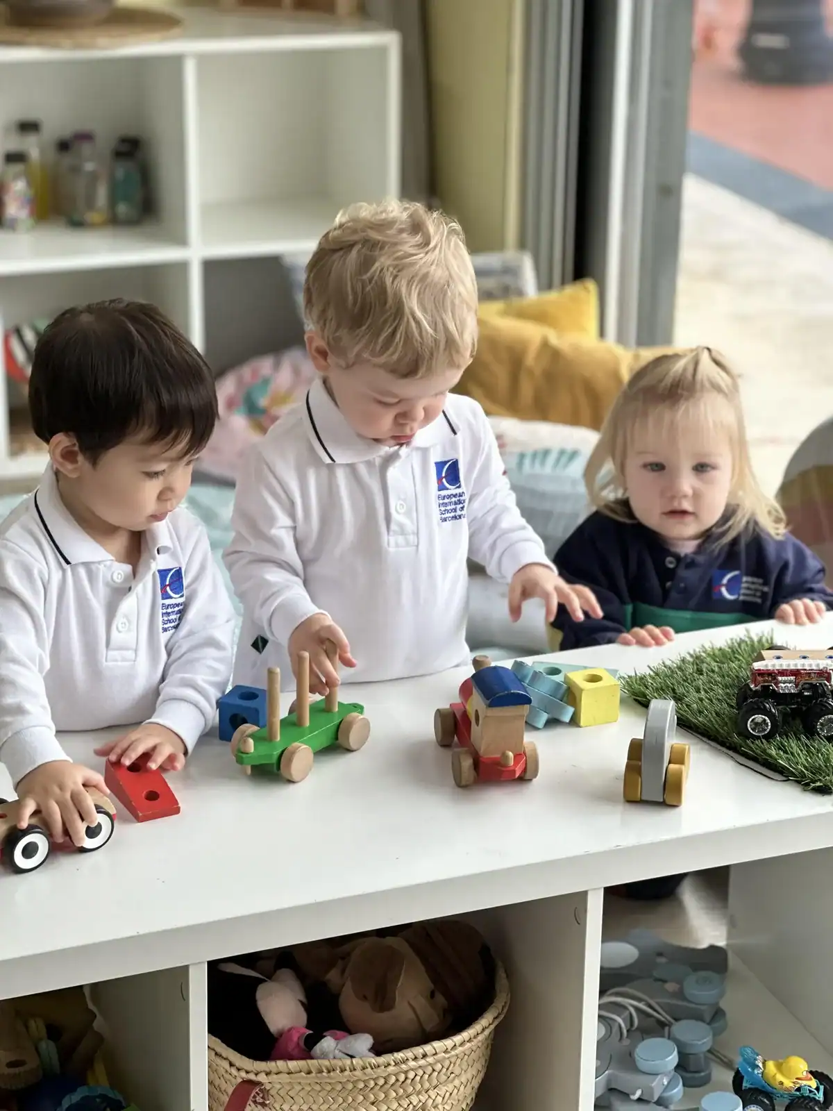 Children playing with wooden toys at a classroom table.