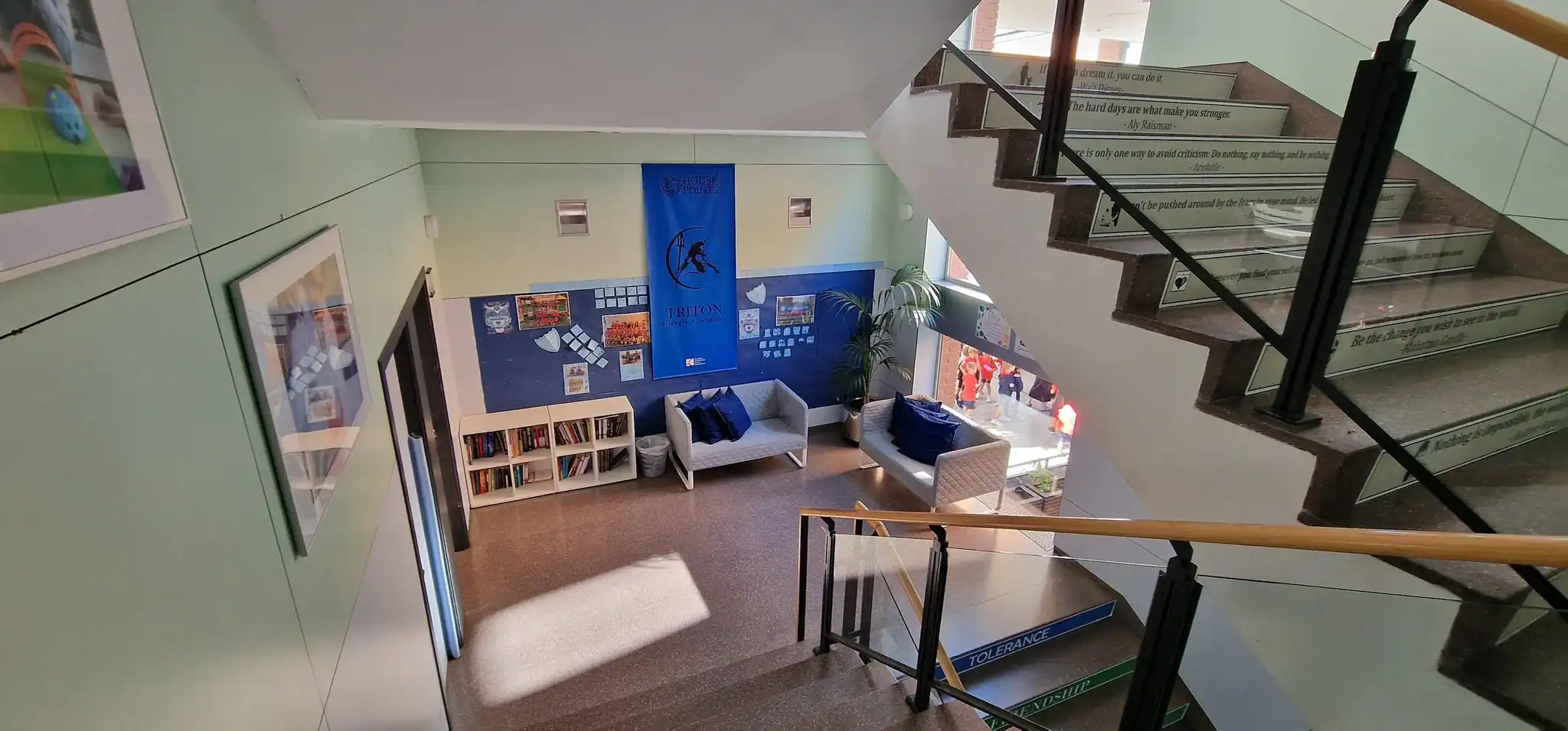 Interior view of a modern school lobby with seating and staircase.
