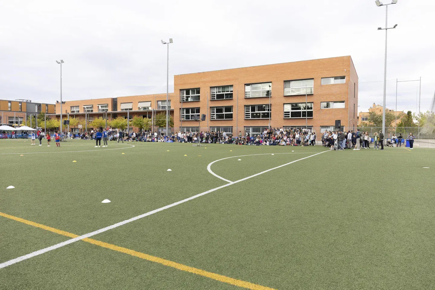 Groups of students on a soccer field outside a brick school building at European International.