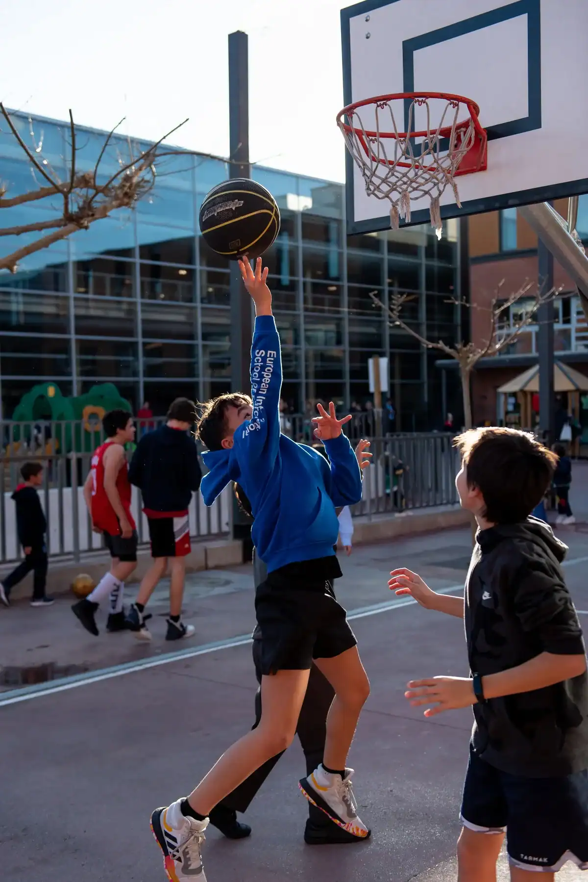 Young student going for a layup during outdoor basketball game at school.