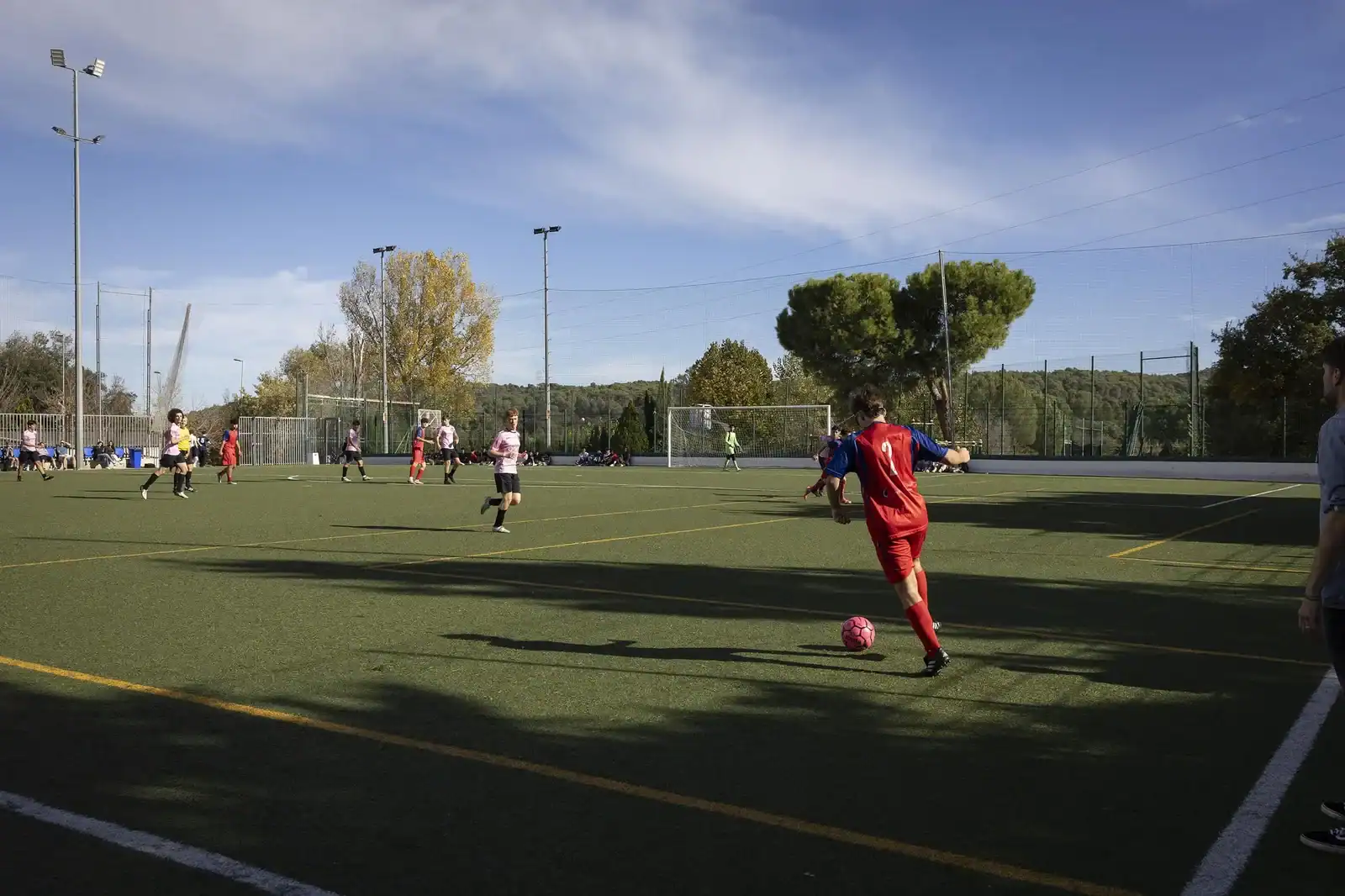 Soccer players in a match on an outdoor artificial turf field.