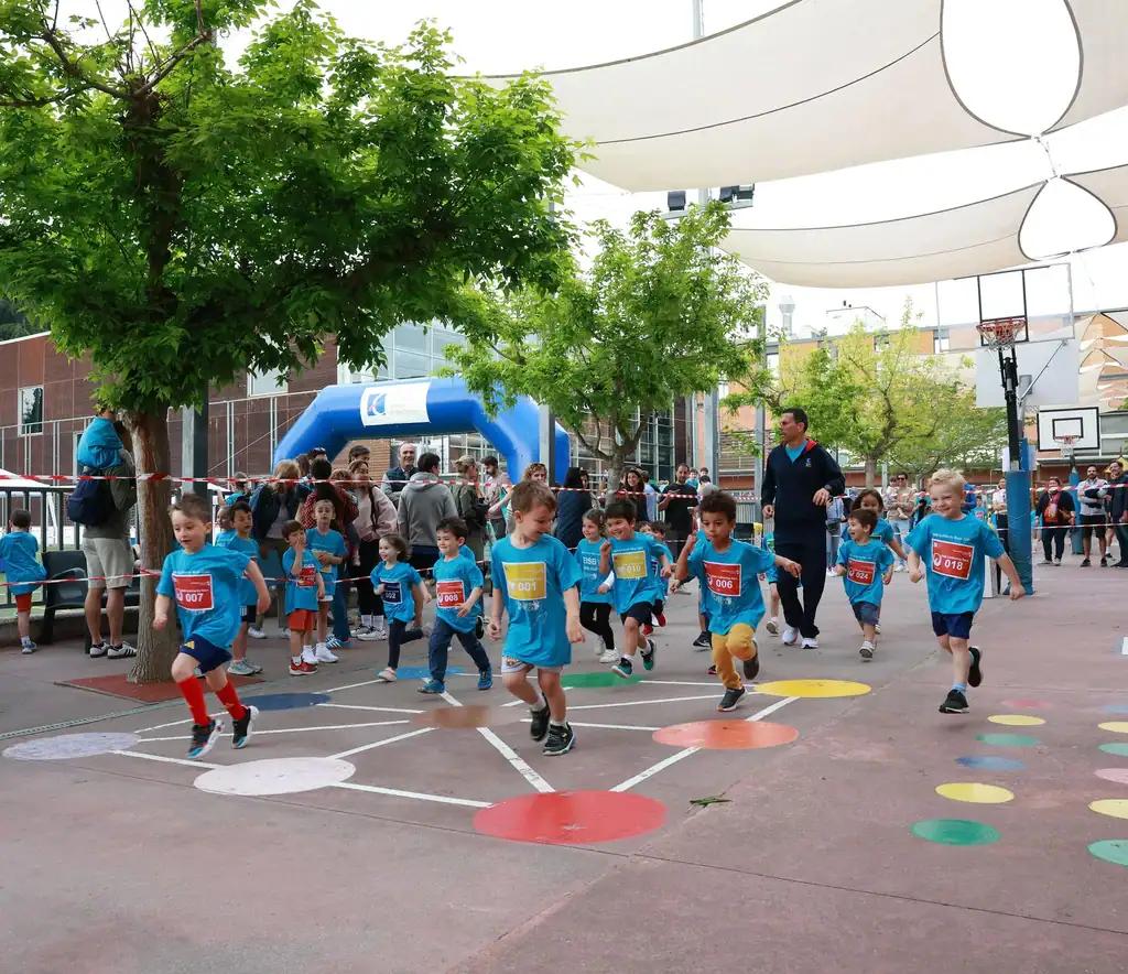 Children in blue shirts start a jump rope race on a school playground.