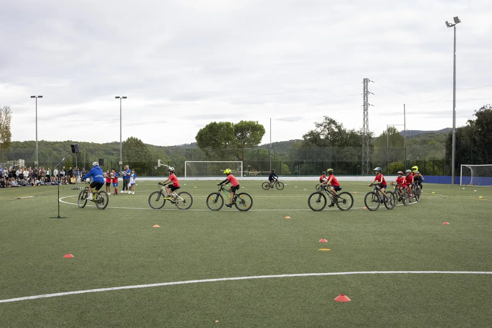 Group of students riding bikes during a school activity on a sports field.