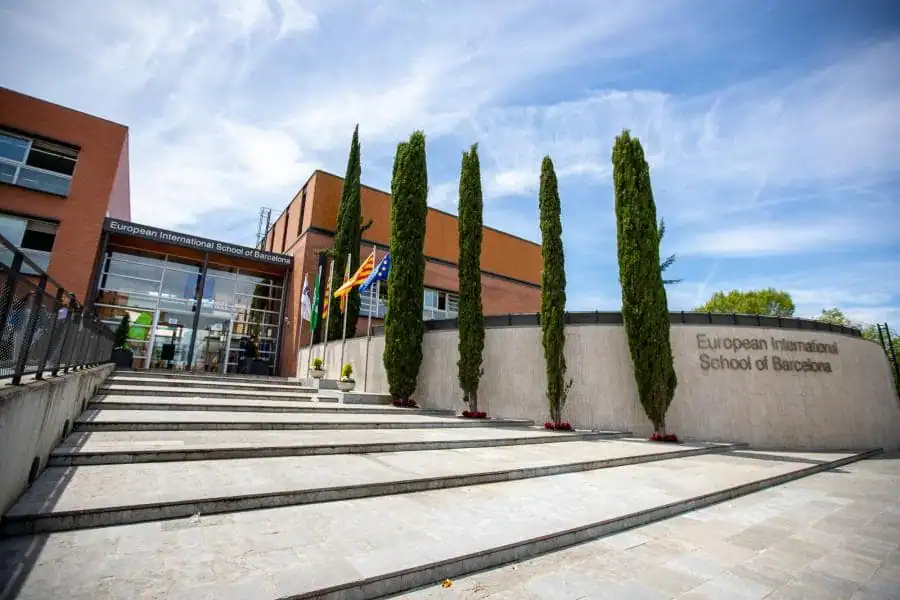 European International School of Barcelona entrance with tall trees and steps.