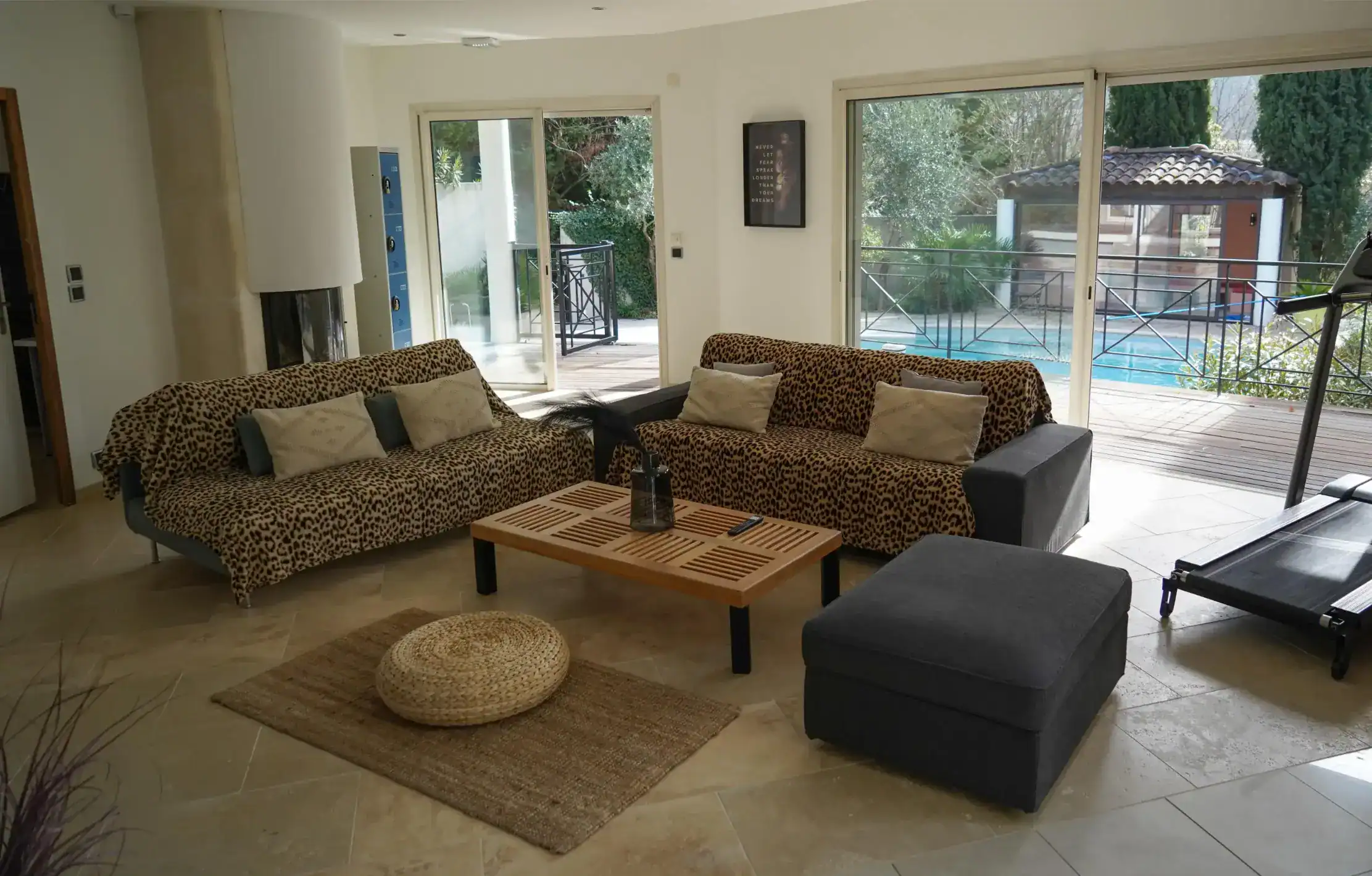 Spacious living room with large windows, stylish sofas, and access to outdoor pool area, ideal for modern educational environments.