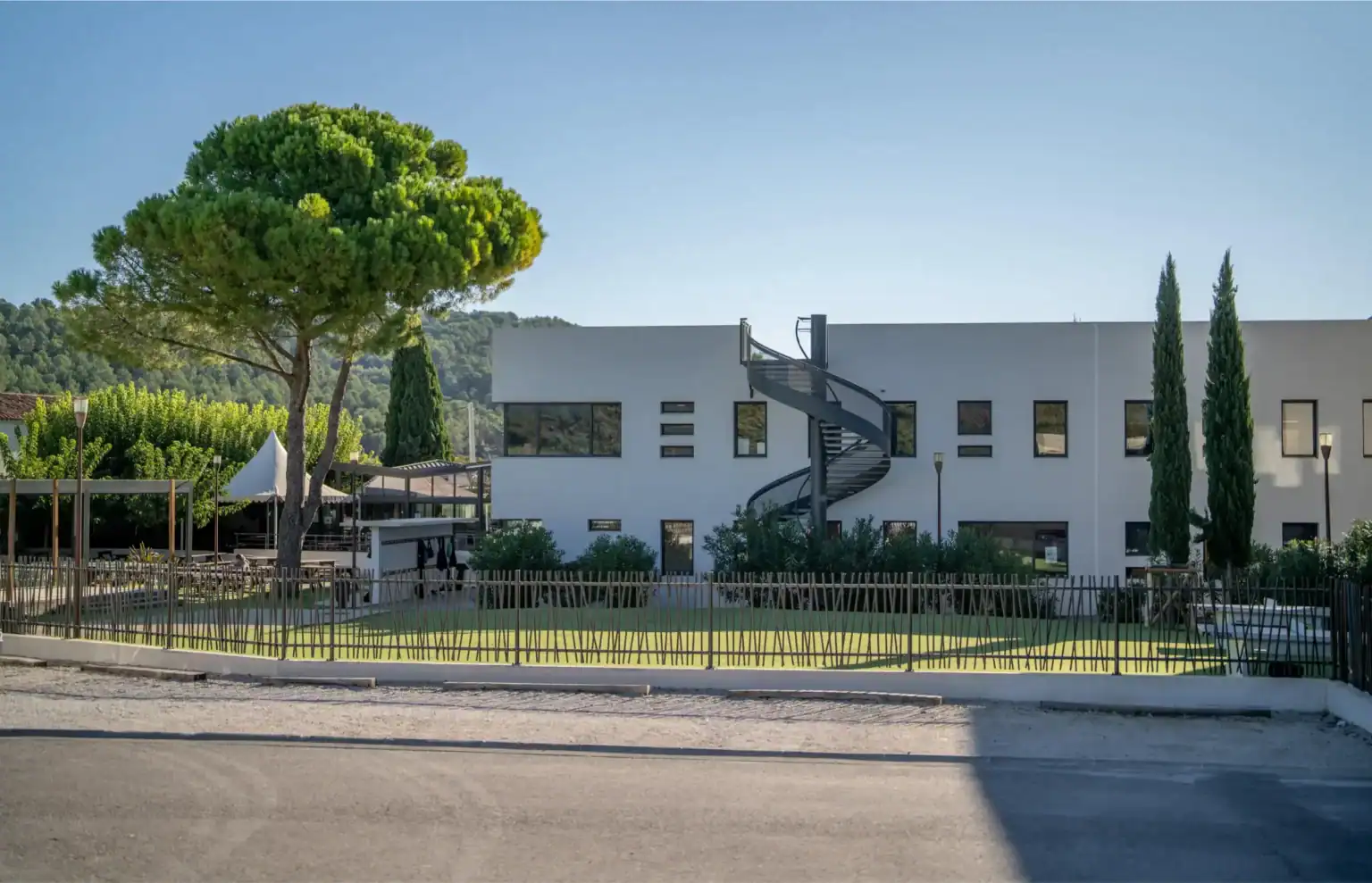 Modern white school building with outdoor playground, lush trees, and a spiral staircase, part of World Schools educational network.