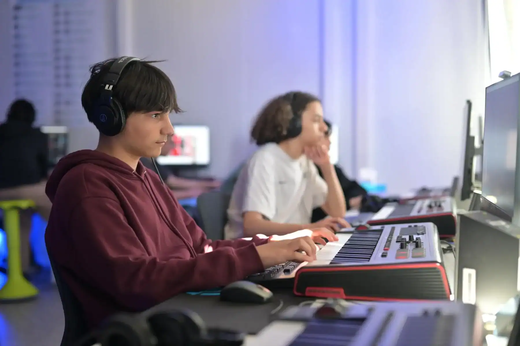 Students working on music production at a computer station in a modern classroom.