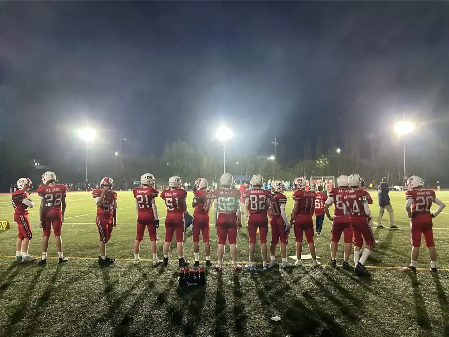 Football team practicing at night under stadium lights.