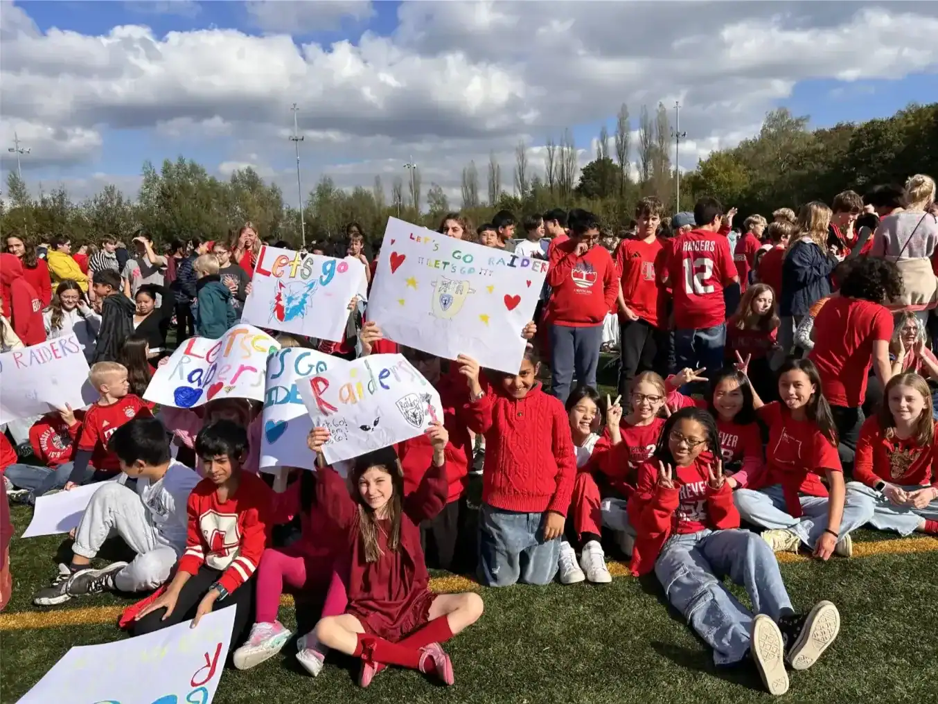 Students holding colorful signs during outdoor school event at International School of Brussels.
