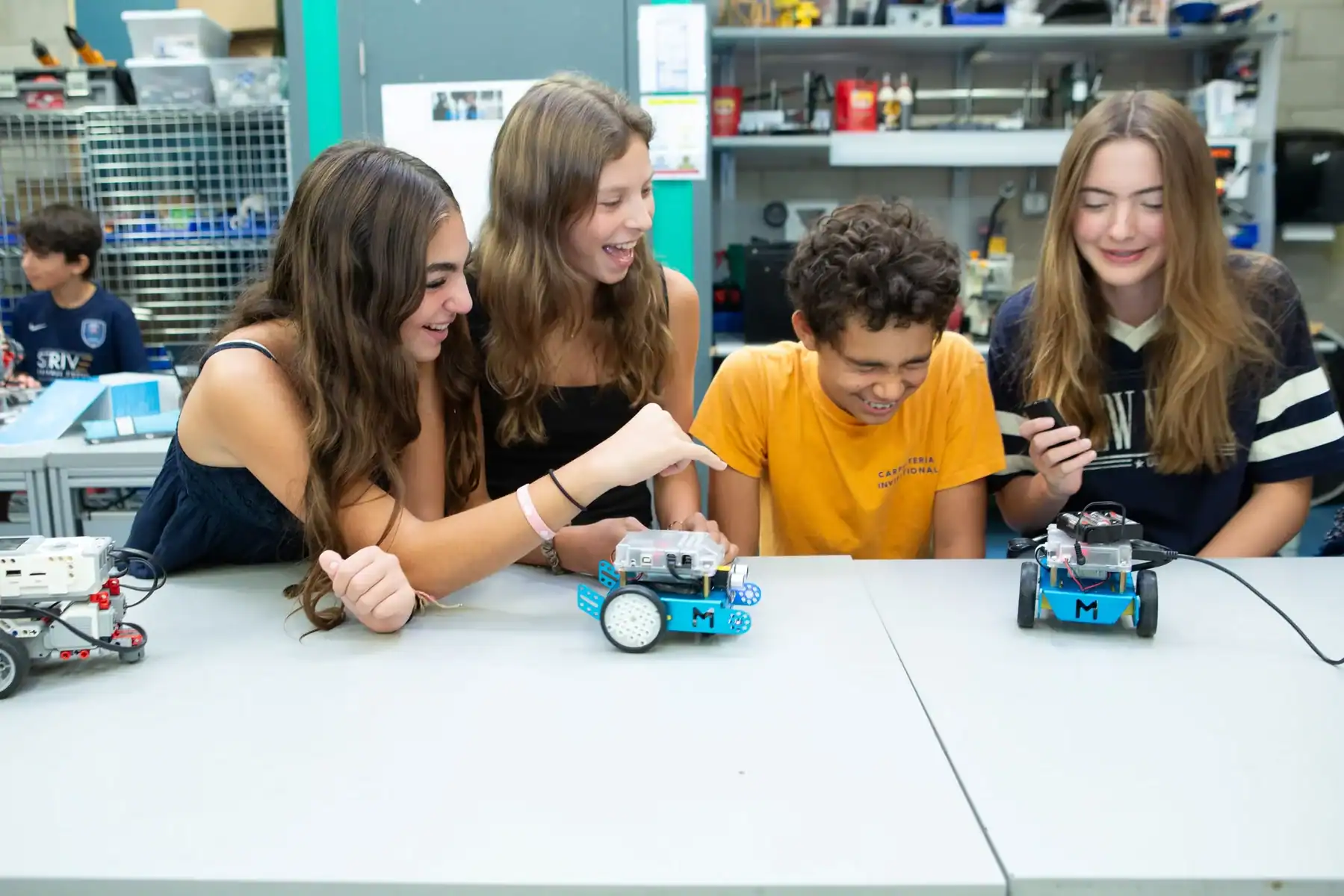 Students programming small autonomous robots in a classroom for STEM education.