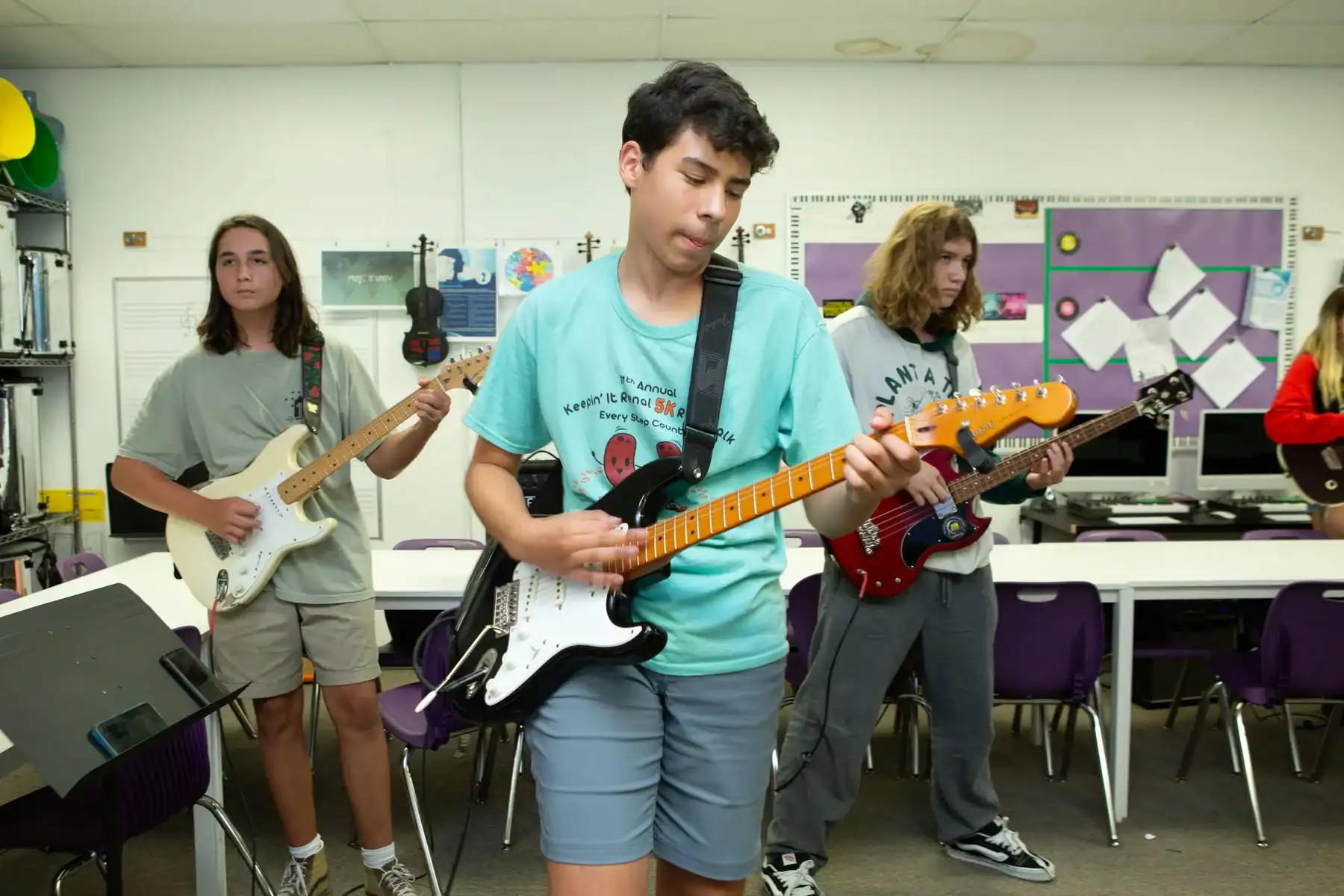 Students playing electric guitars in a classroom band".