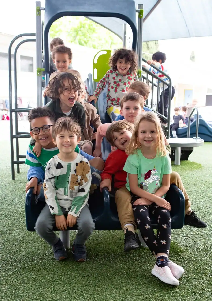 Group of happy children on a playground slide at a school.