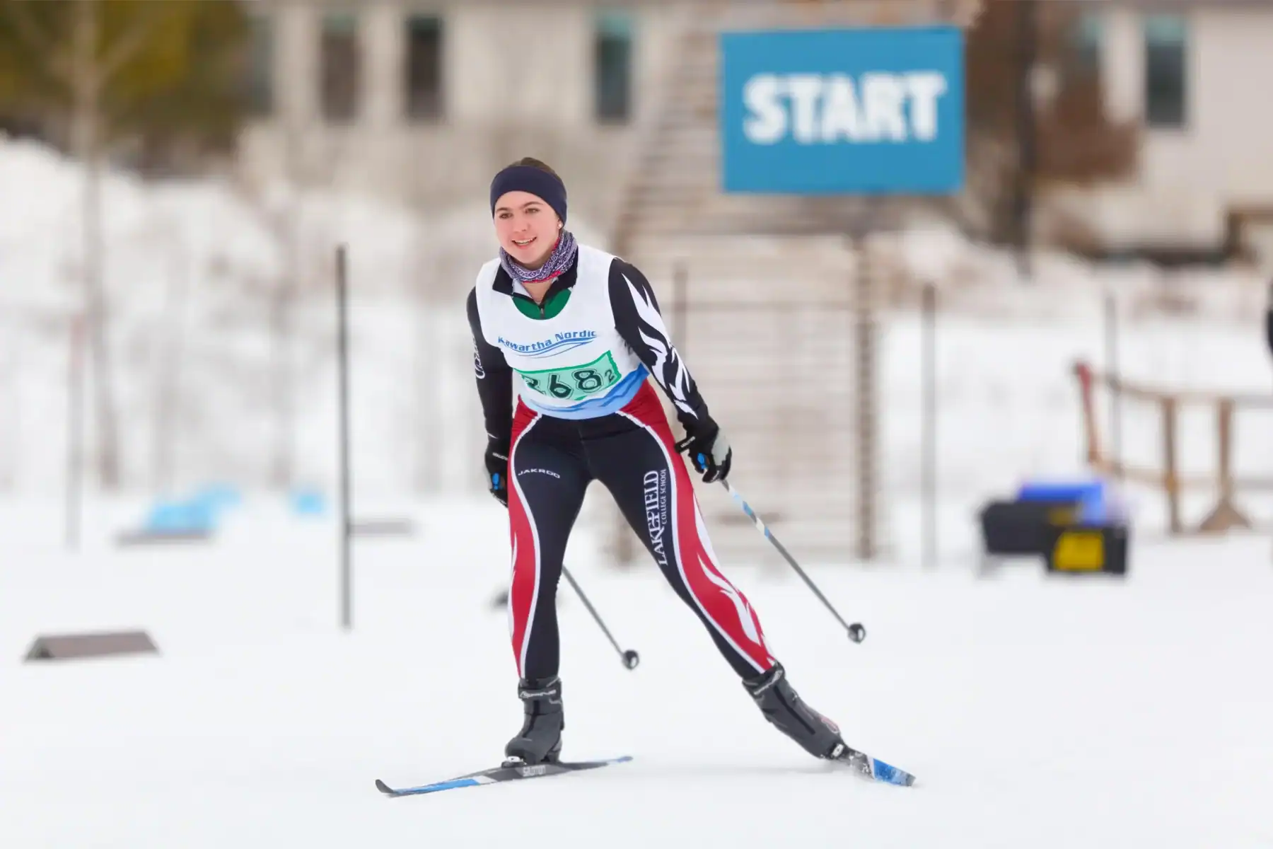 Young athlete skiing at the start line during a winter sports event.