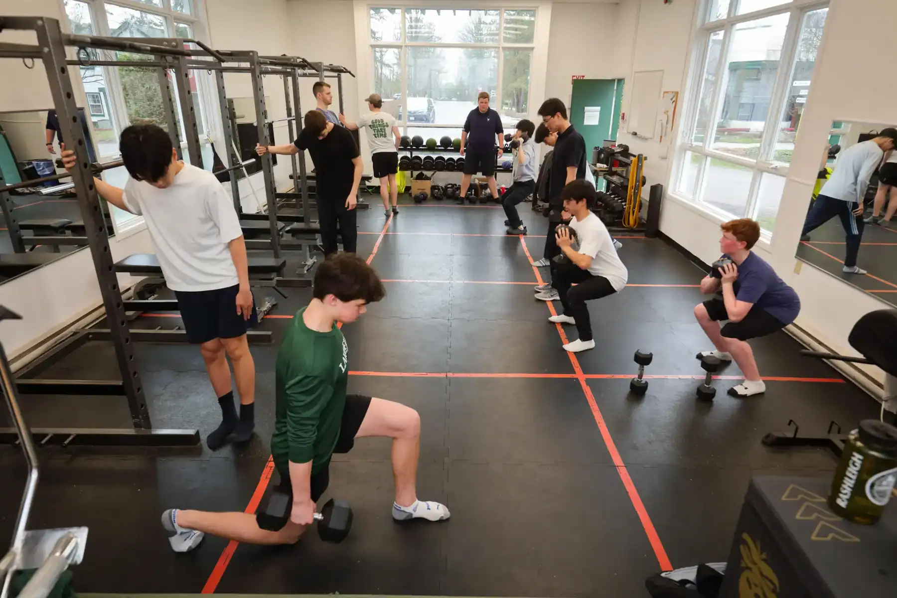 Modern gym with students engaging in strength training exercises.