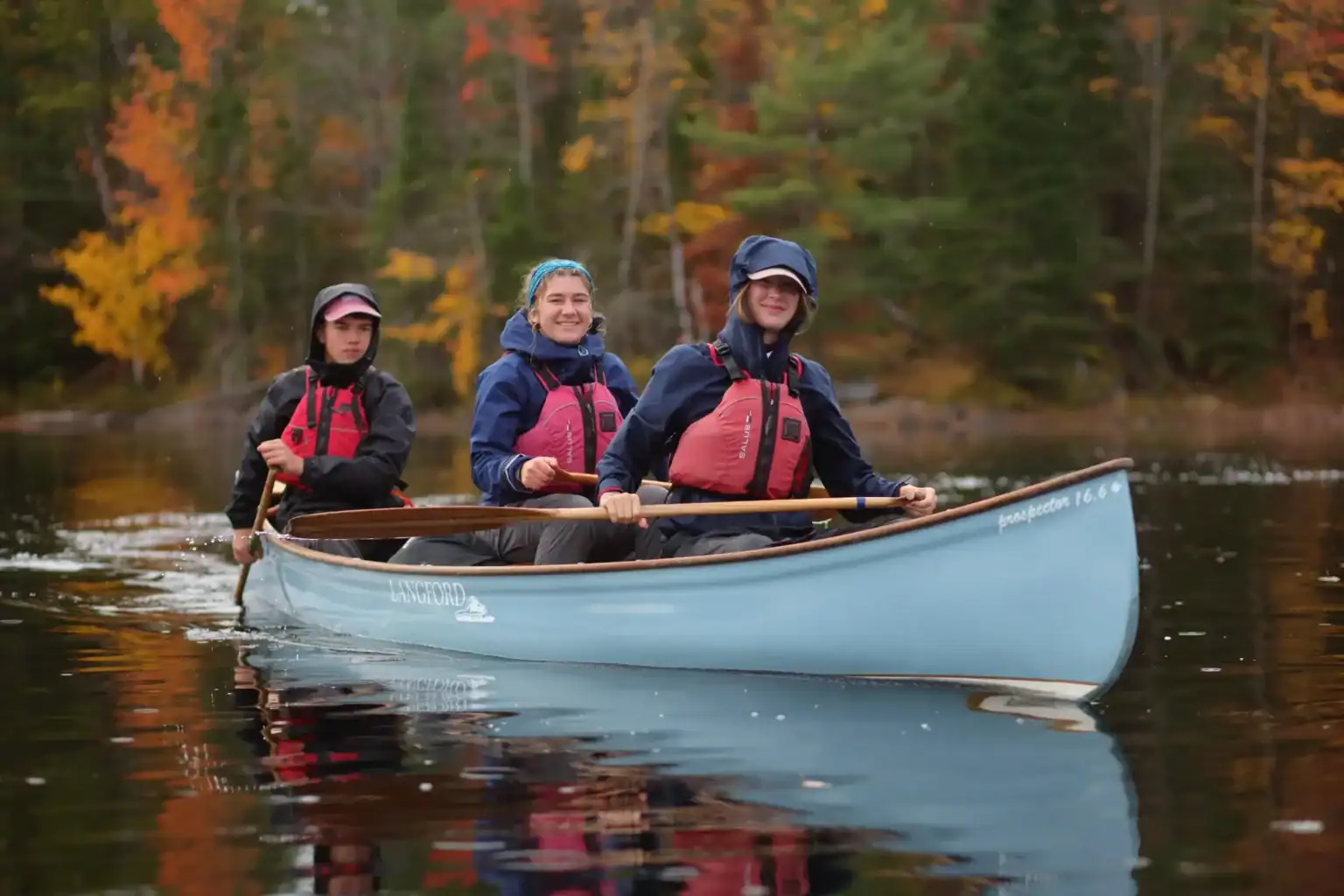 Canoe trip at Lakefield College School with students paddling on a calm lake surrounded by autumn fo.
