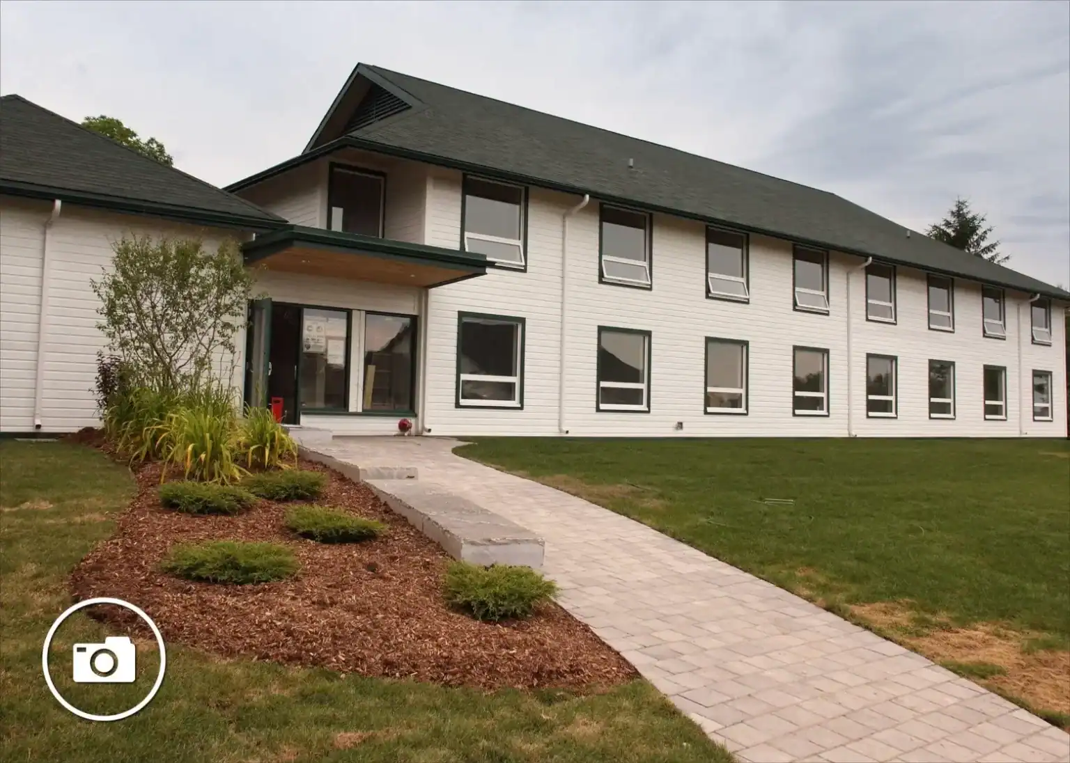School building with landscaped entrance and green lawn.