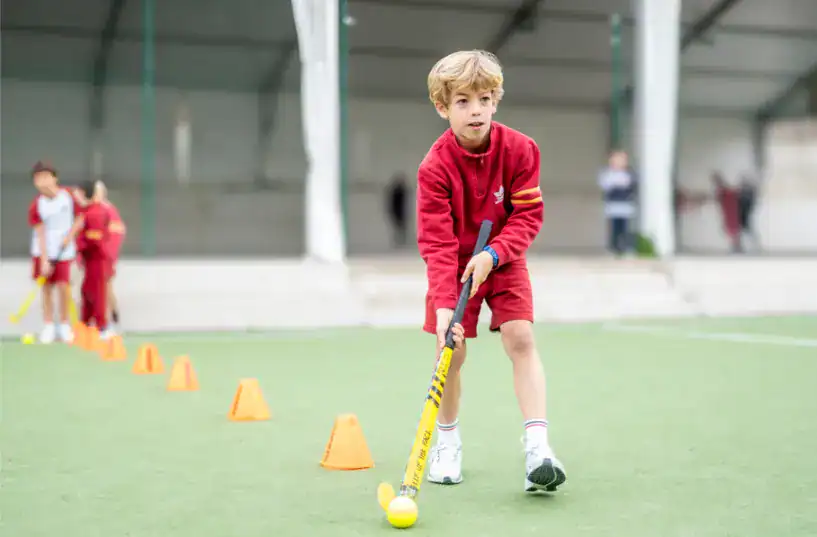 Young boy playing field hockey at Thames British School in Madrid.