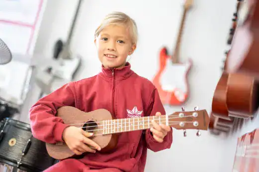Young girl playing ukulele in music classroom at Thames British School Madrid.