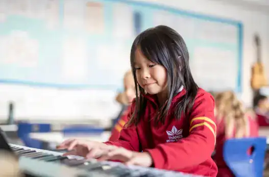 Young girl playing piano in classroom at Thames British School Madrid.