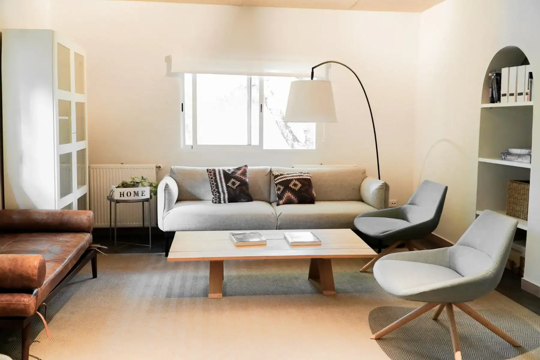 Bright, cozy living space featuring contemporary sofas, armchairs, and a large window for natural il.