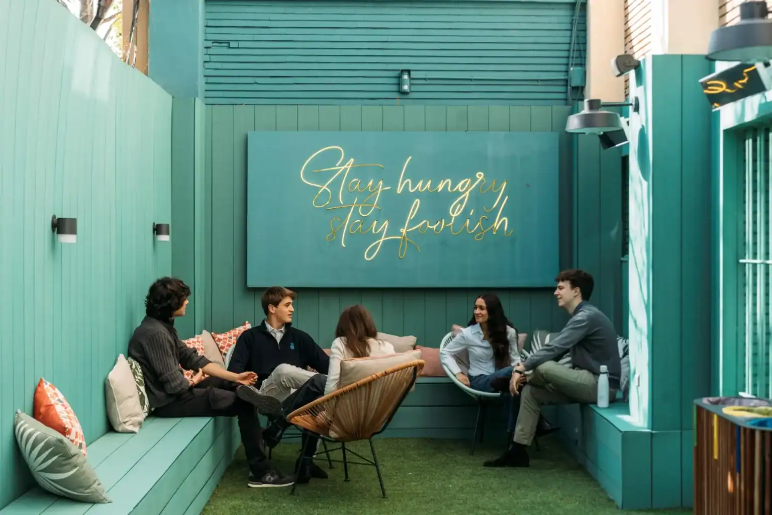 A group of young students engaging in a lively discussion in a modern, vibrant outdoor space at The.