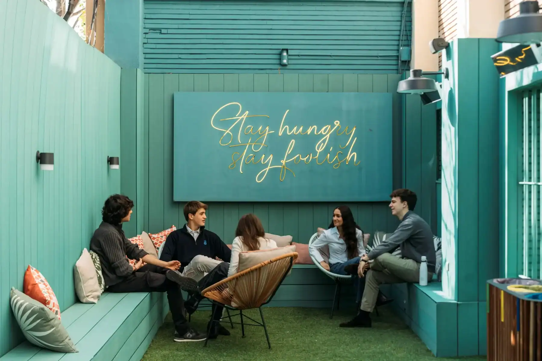 A group of young students engaging in a lively discussion in a modern, vibrant outdoor space at The.