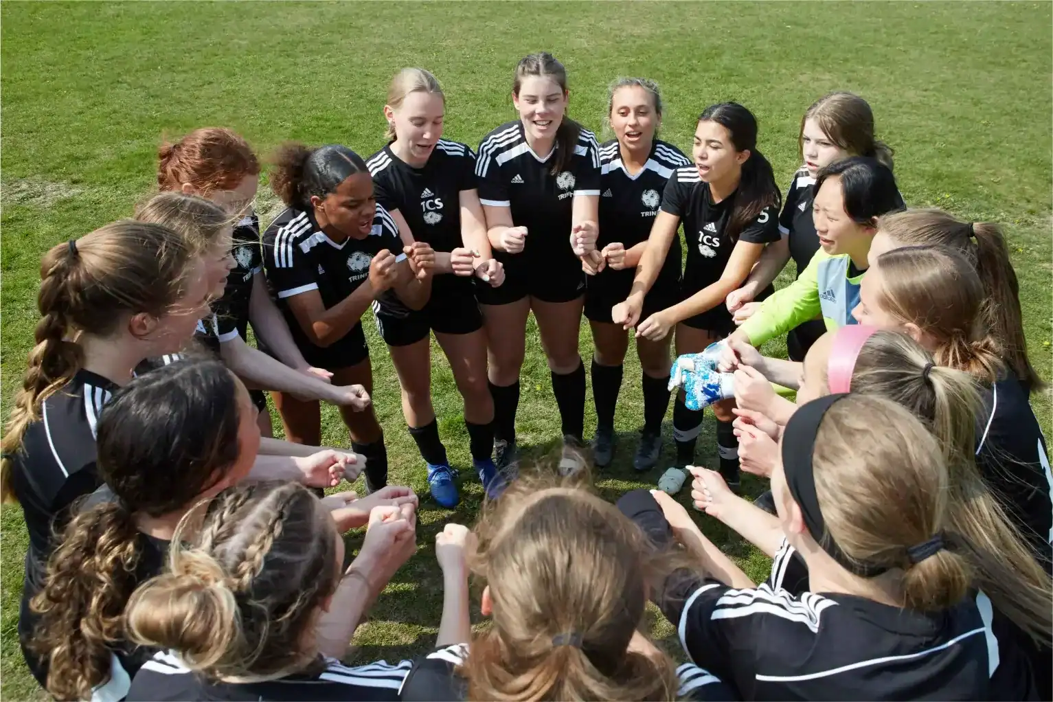 Girls' soccer team huddles on the field before a match.