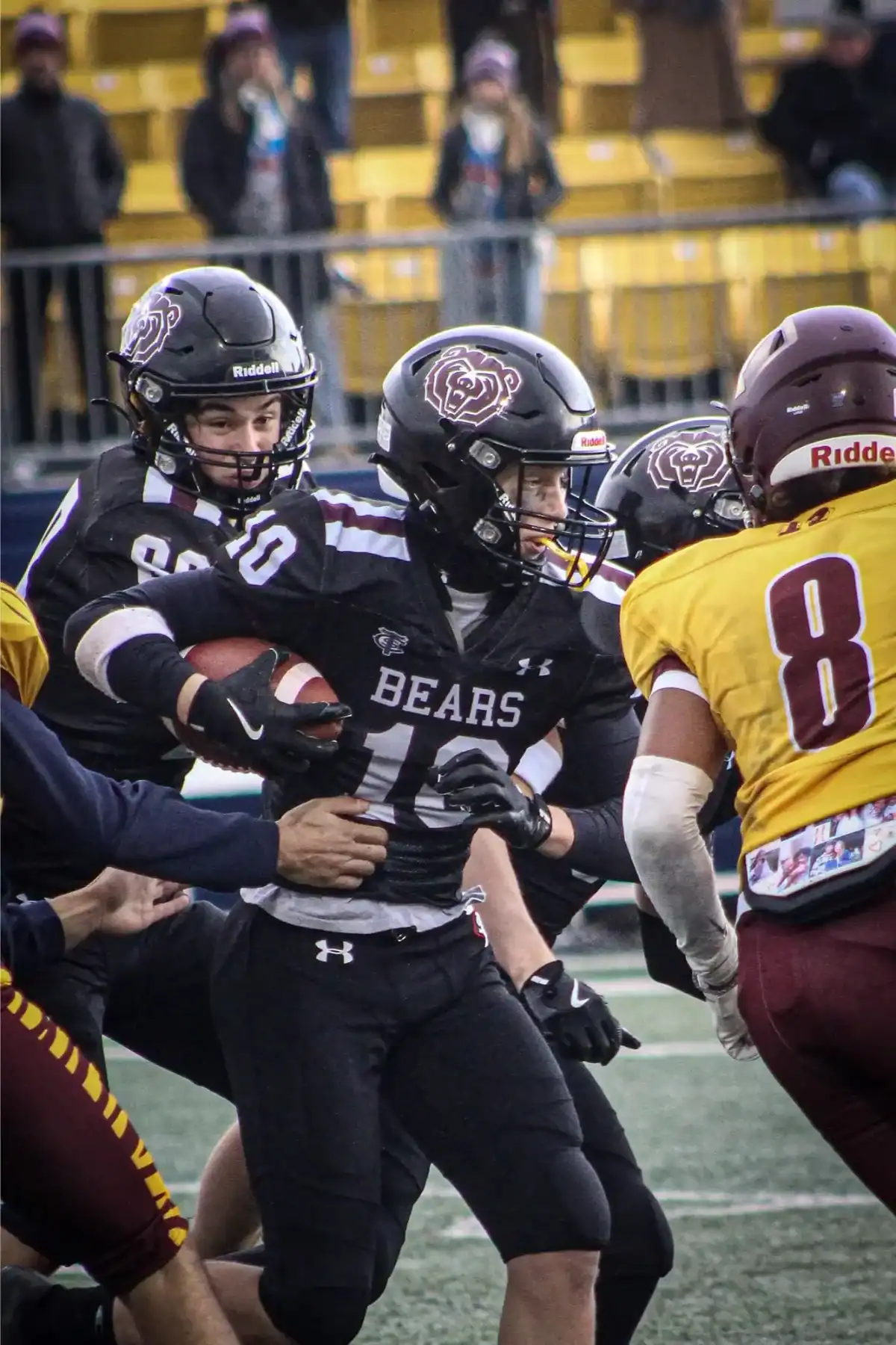 High school football game with players in action on the field.