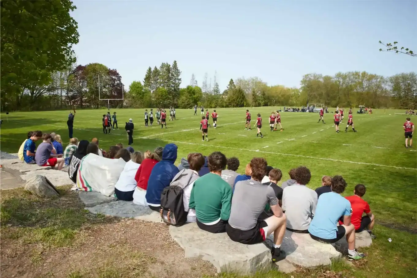 Students watching a rugby match on a sunny day at Trinity College School.