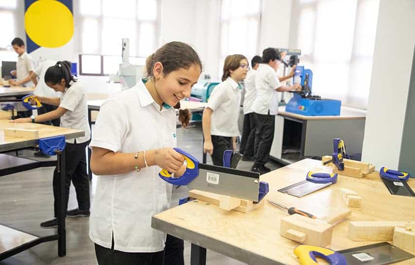 Innovative school workshop with children using woodworking tools in a modern classroom setting.