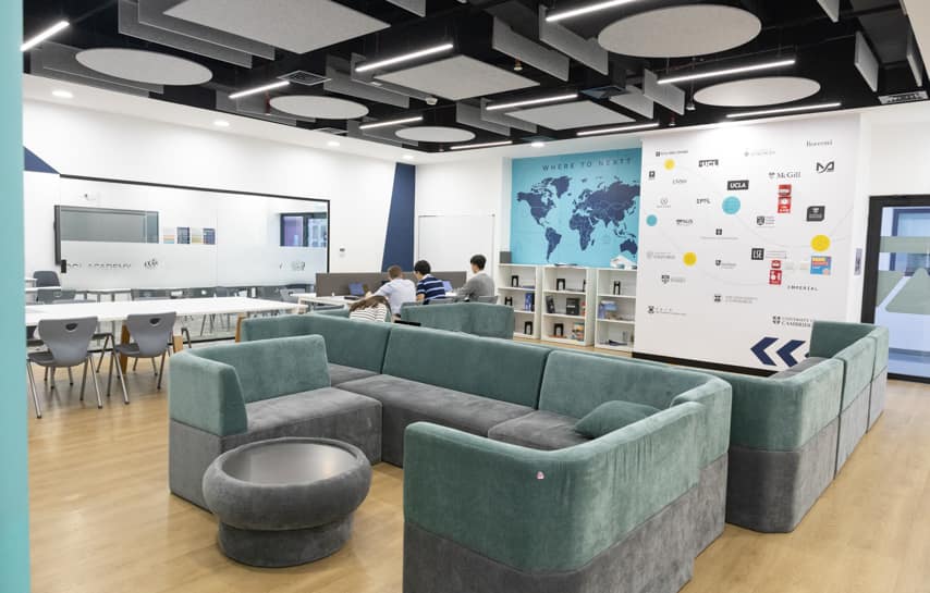 Modern international school lounge with collaborative study areas and world map display for global learning.