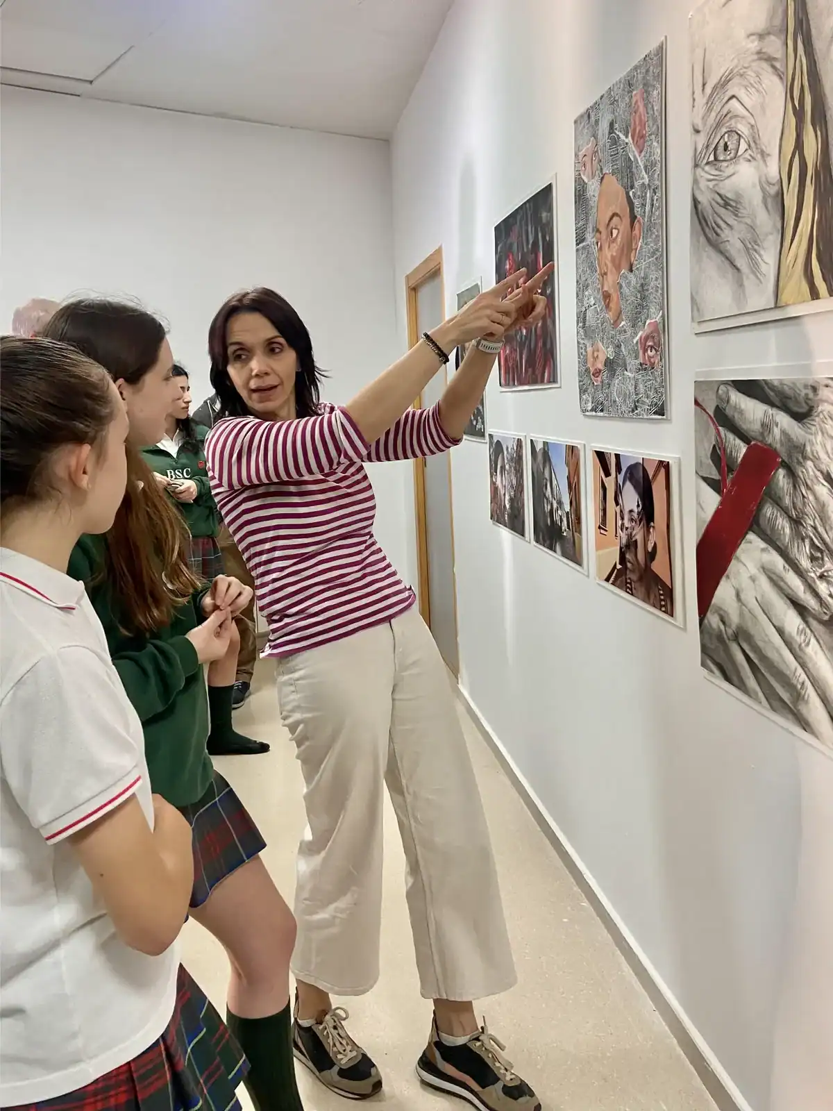 A woman explaining artwork to students in an art gallery.