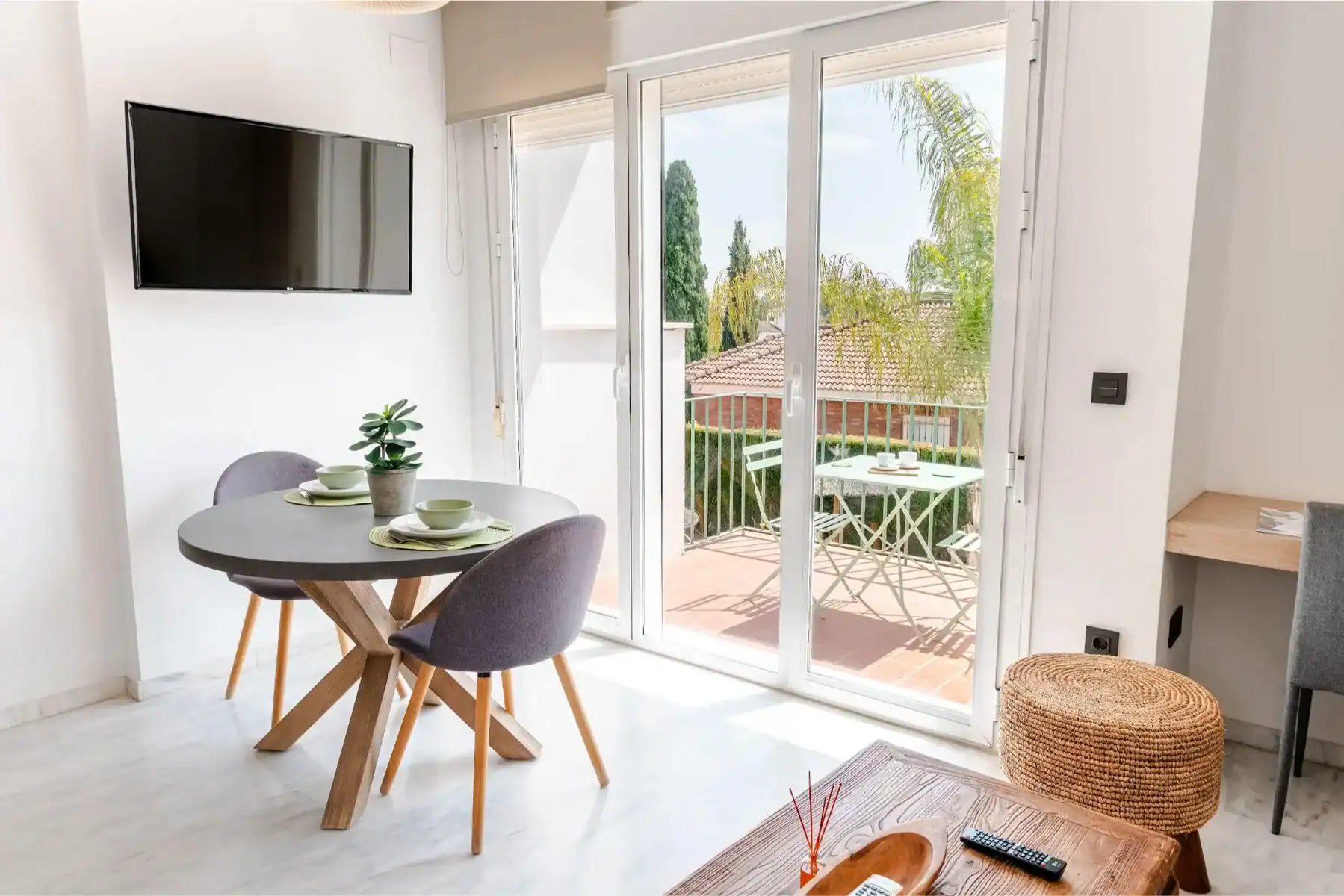 A comfortable dining area with large glass doors leading to a balcony, bright and modern interior.