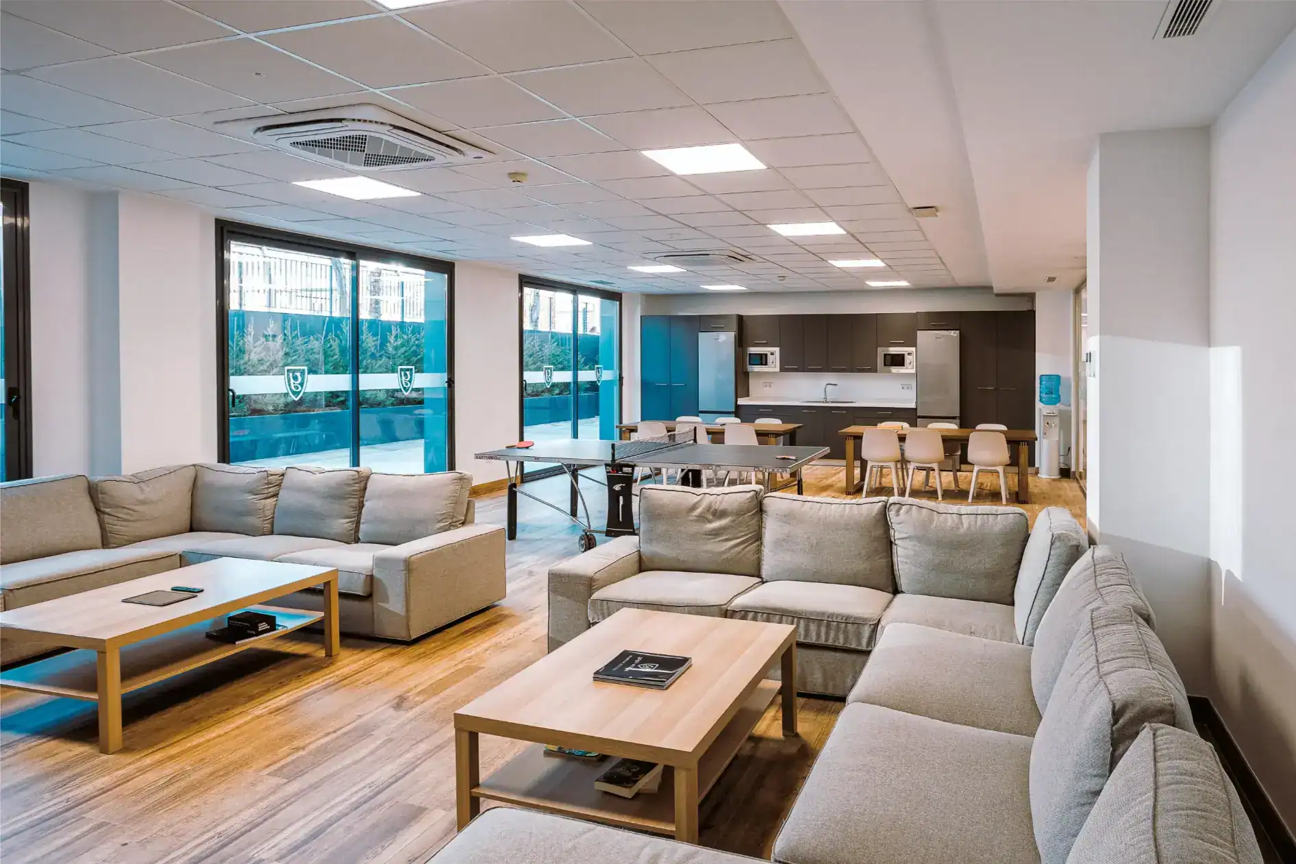 Modern school lounge area with comfortable seating and kitchenette, ideal for student relaxation and socialization.