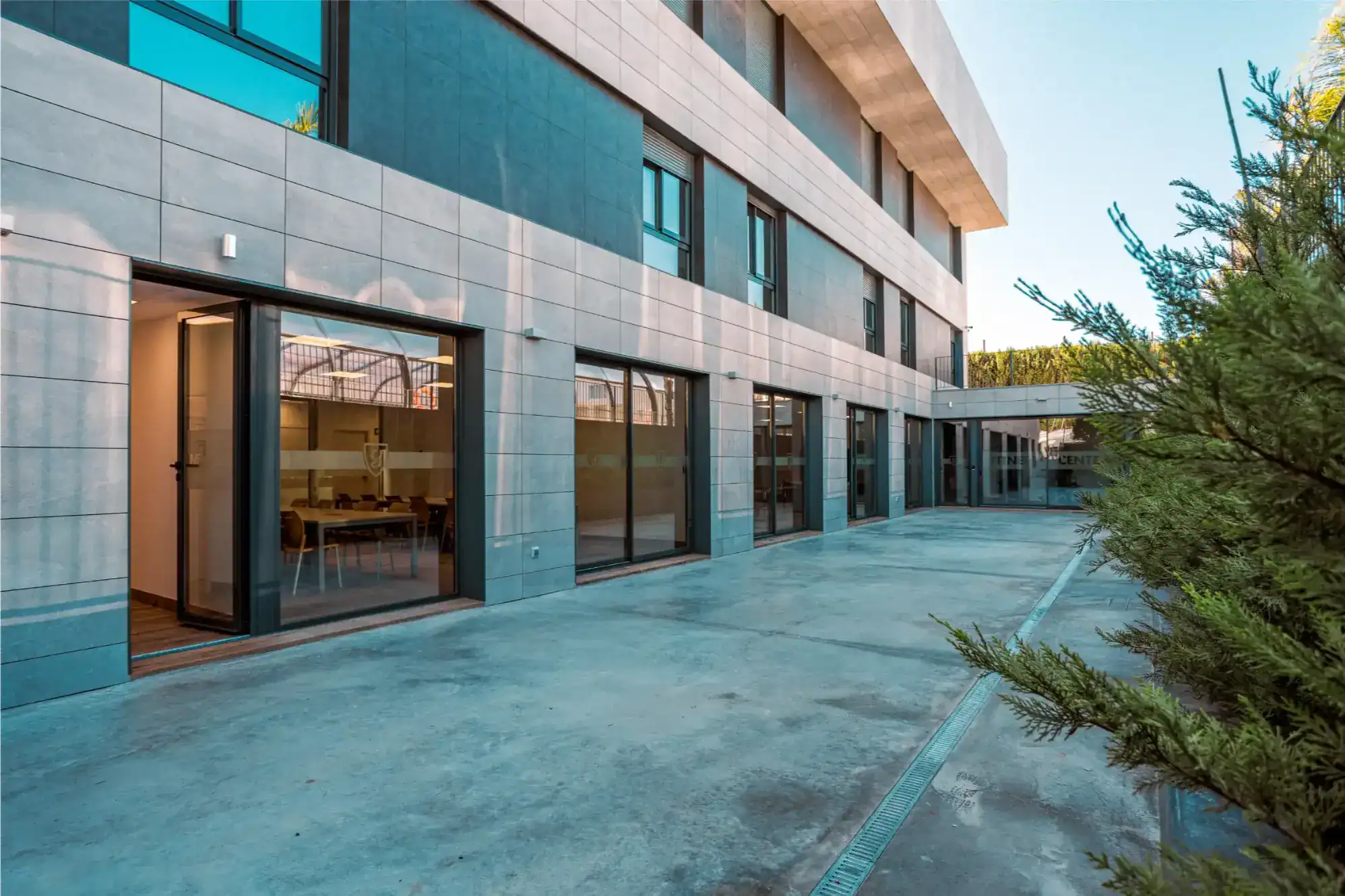 Modern urban school building with glass doors and outdoor patio, ideal for international students.
