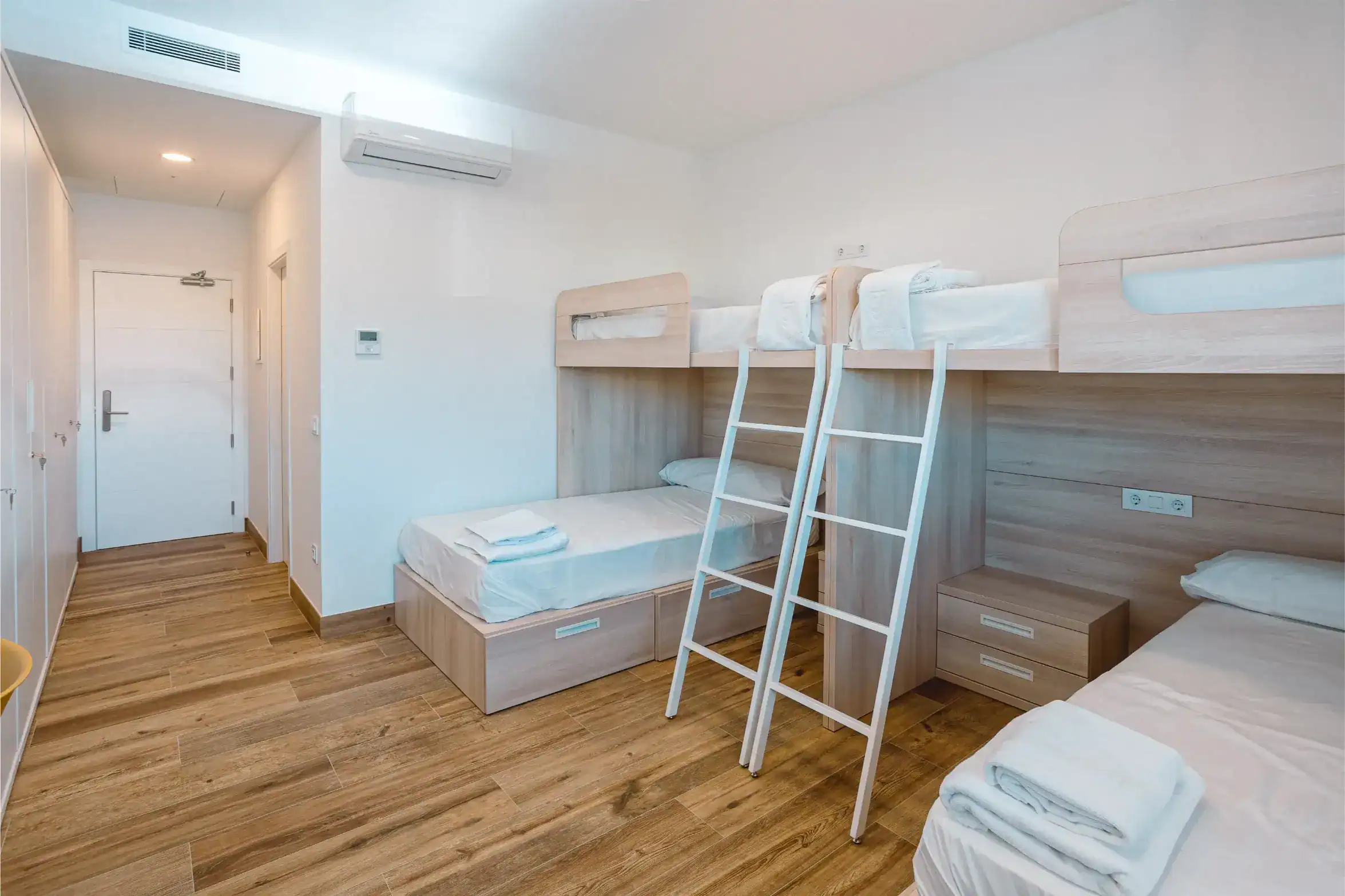 Bright modern bedroom with bunk beds, wooden flooring, and minimalist decor, perfect for students at World Schools.