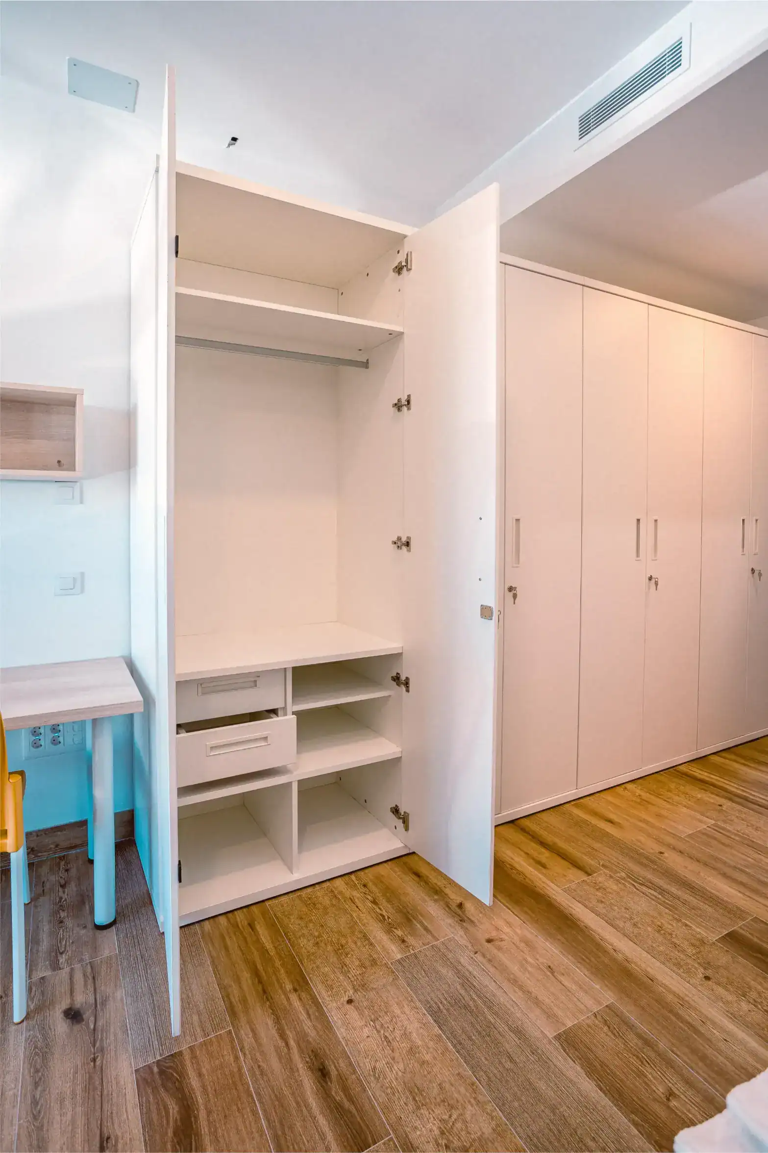 Open white wardrobe with shelves and drawers in a modern room.