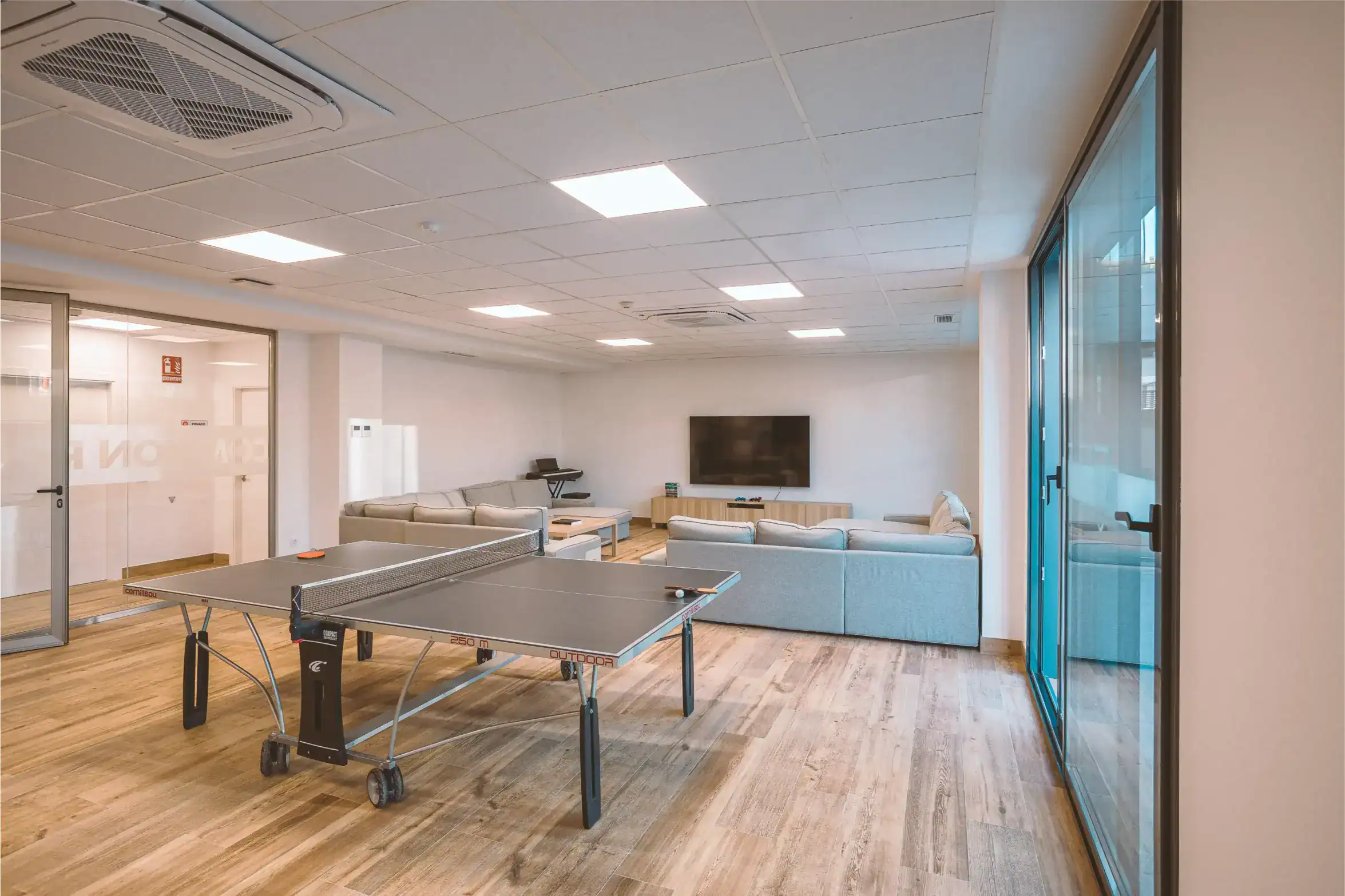 Modern school recreation room with ping pong table and comfortable seating area for students and staff.