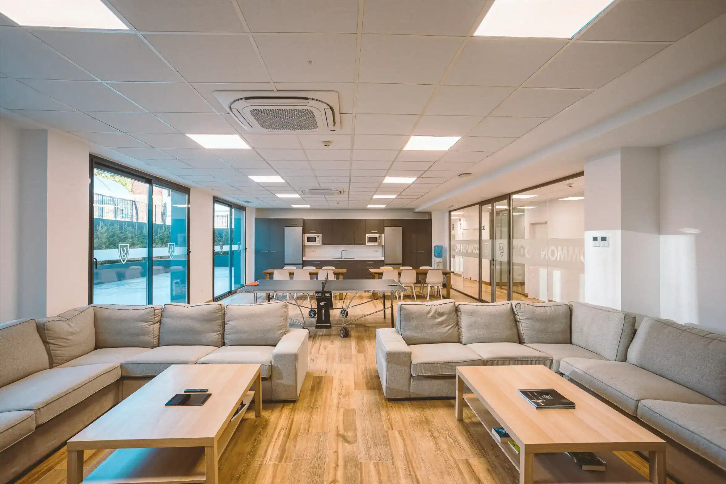 Bright modern school lounge with natural light, comfortable seating, and a student common area.