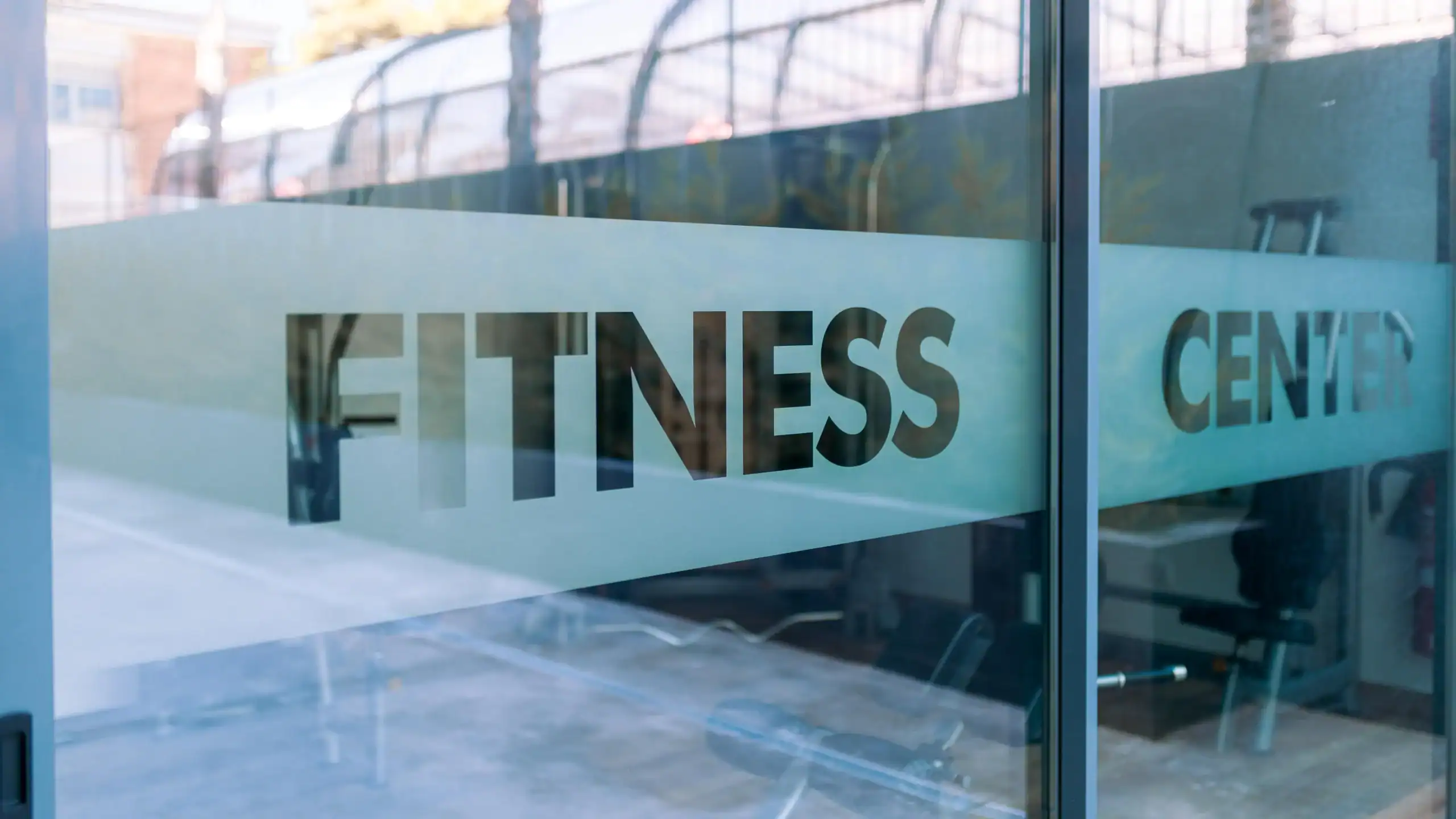 Modern fitness center entrance with clear glass doors, promoting health and wellness.