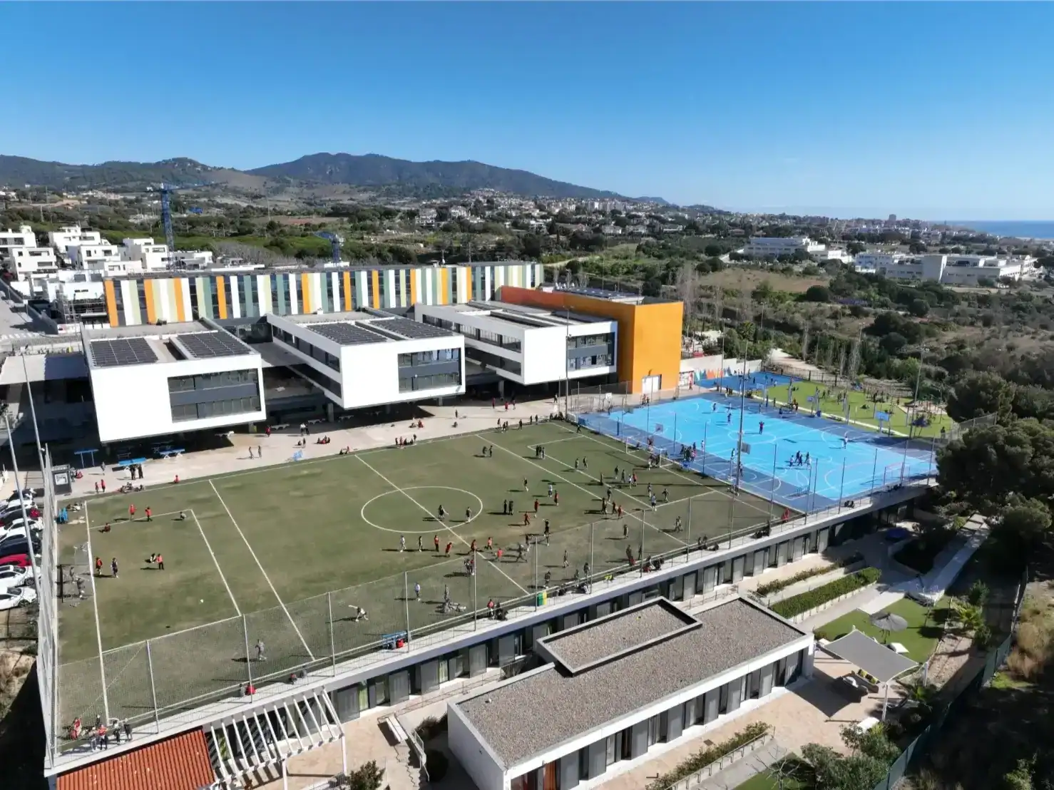 Hamelin-Laie International School Barcelona with sports facilities and scenic mountain views.