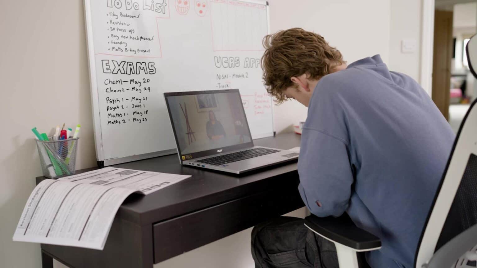 Student engaged in online learning at Nisai Learning with a laptop and whiteboard background.